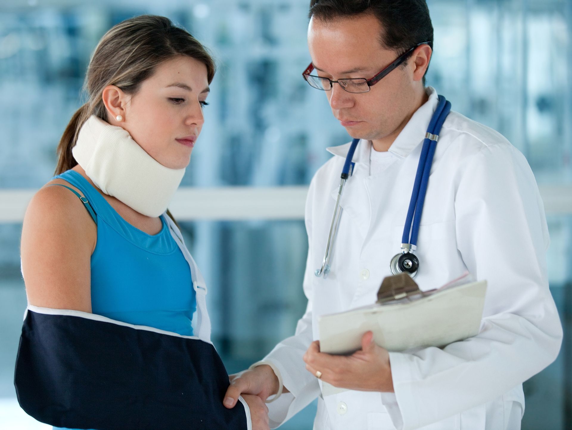 A doctor is talking to a woman with a sling on her arm.