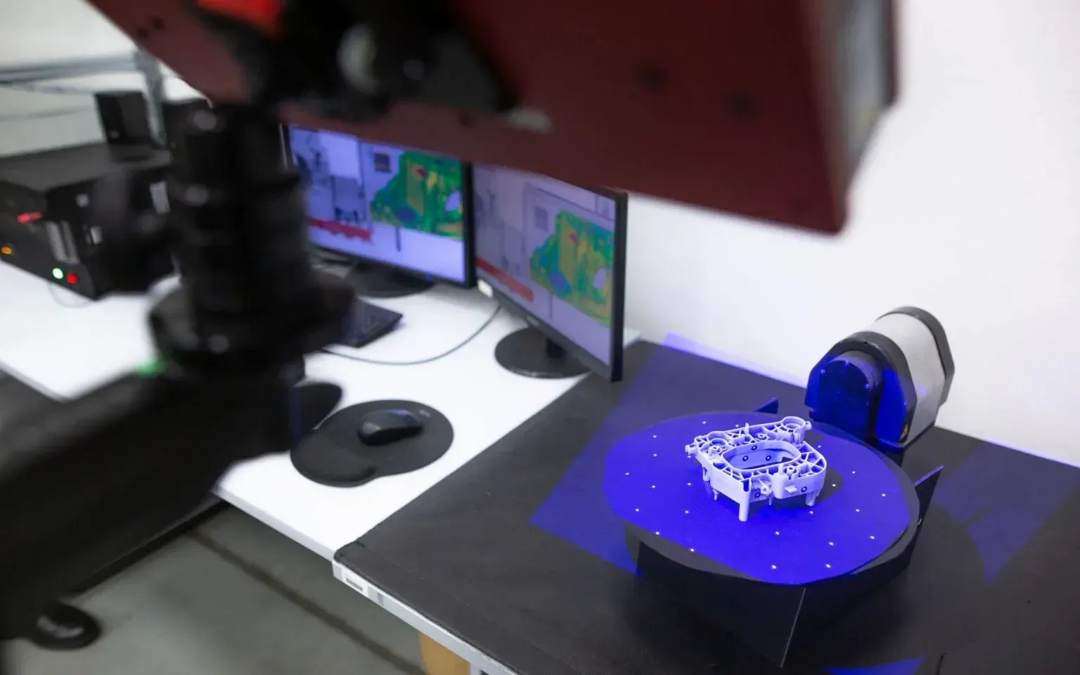 A 3d scanner is scanning a piece of metal on a table.
