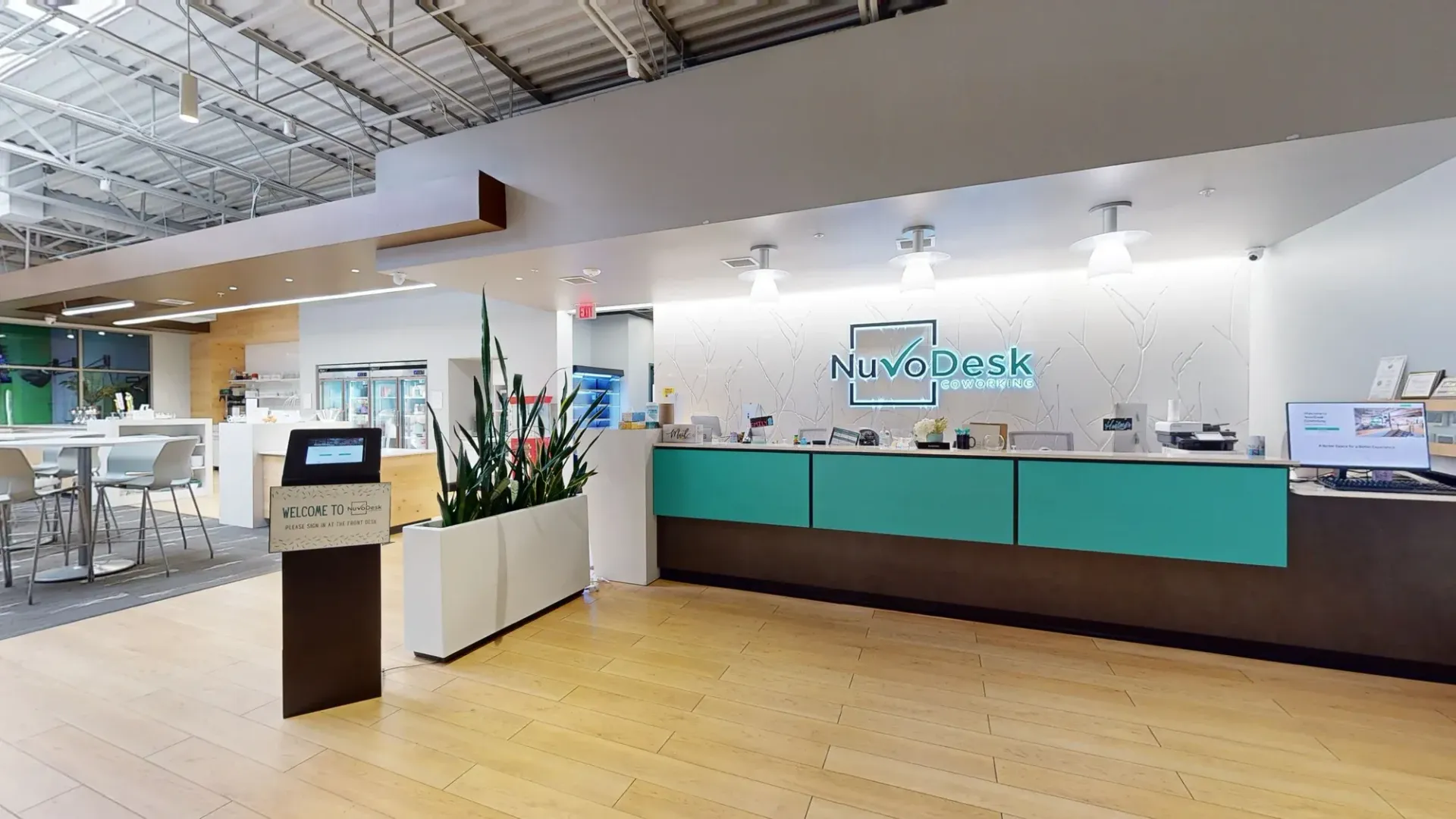 Modern office lobby with reception desk, teal panels, wood floor, and a podium sign on the left