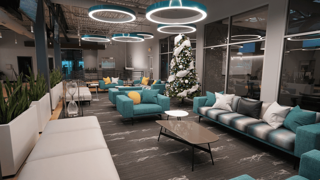 Modern office lounge with teal sofas, white chairs, circular ceiling lights, and a Christmas tree