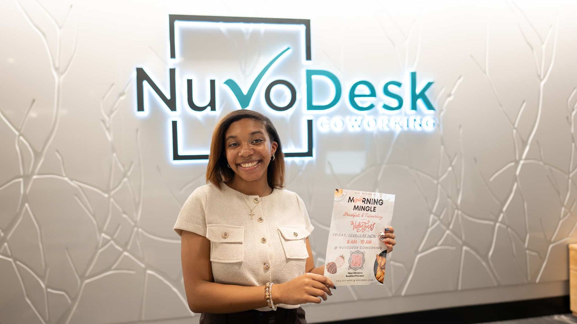 Woman standing at NuvDesk reception, smiling and holding a brochure