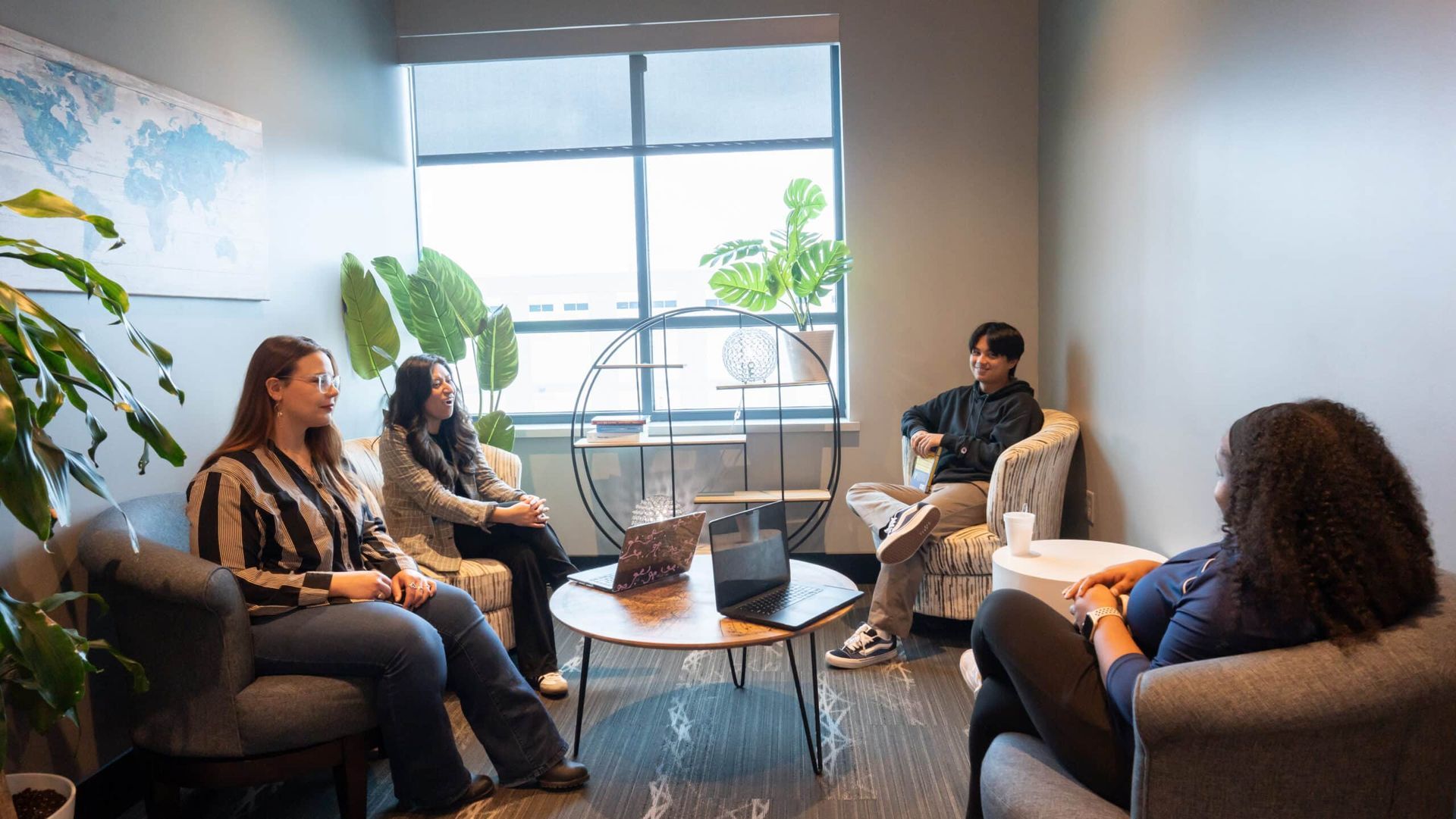 People seated in a bright office lounge having a casual meeting around coffee tables.