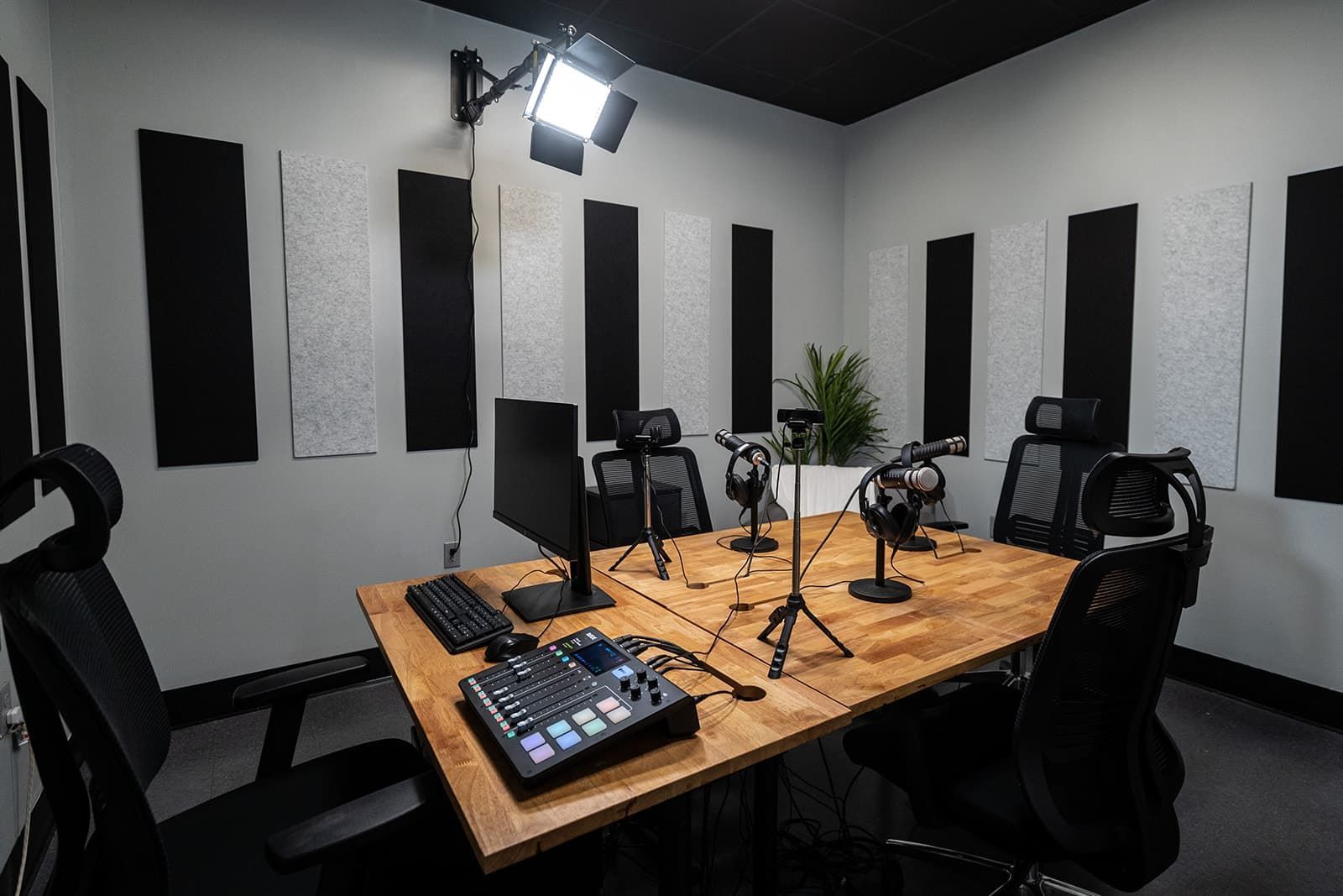 Podcast recording studio with microphones, mixing boards, chairs, and acoustic wall panels