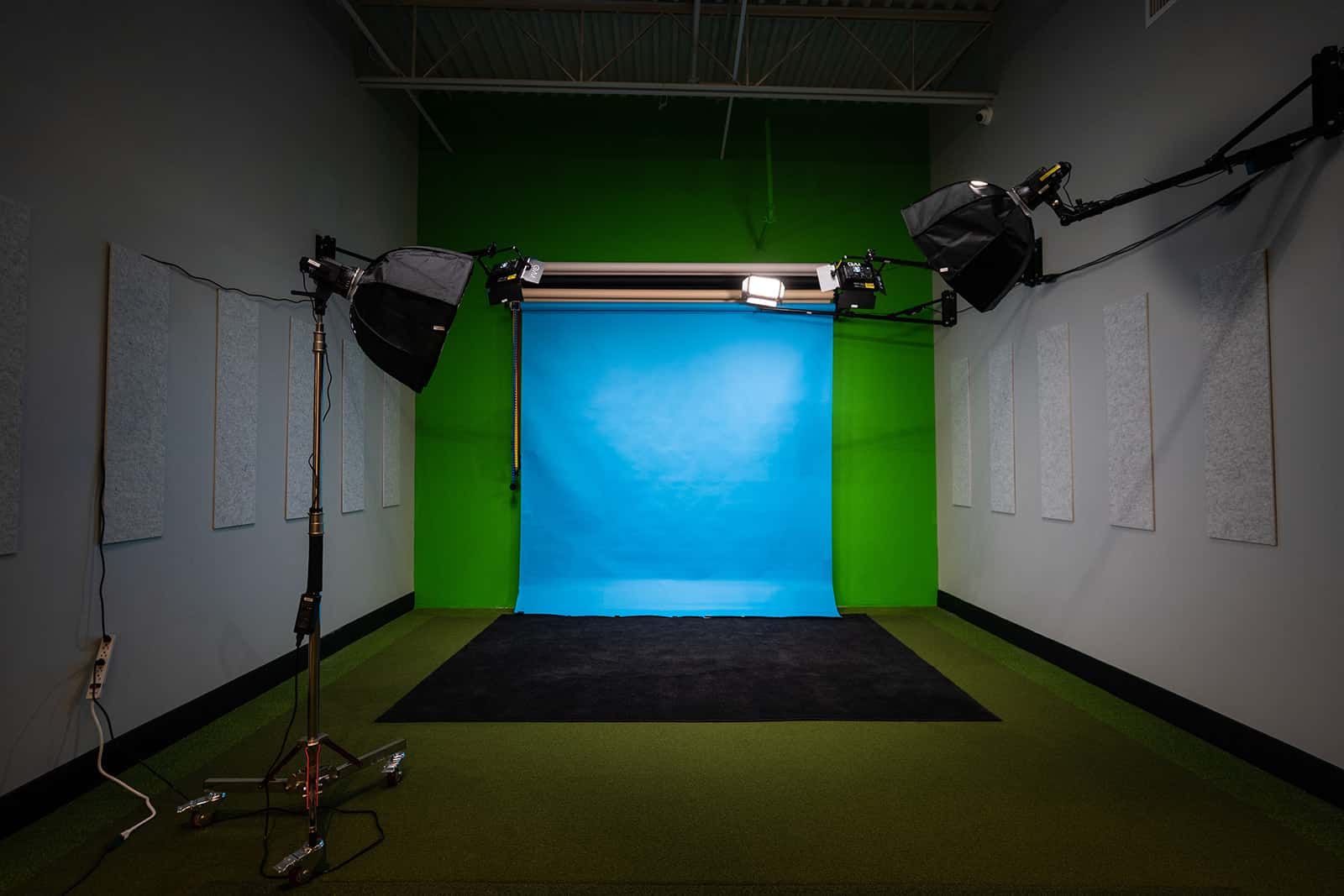 Empty studio set with blue backdrop, green side panels, and studio lights on both sides