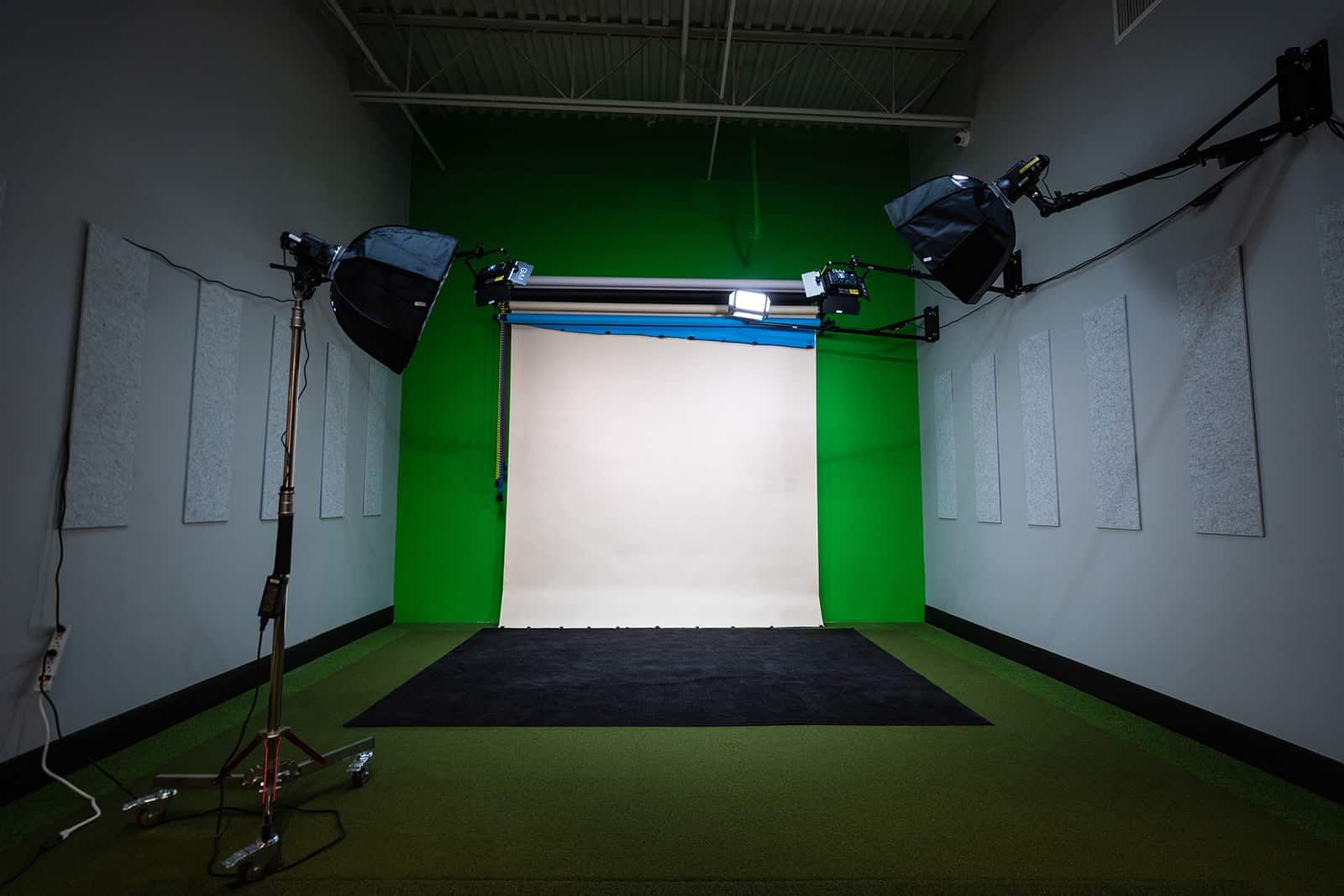 Empty indoor studio with a green screen backdrop and lighting equipment on both sides