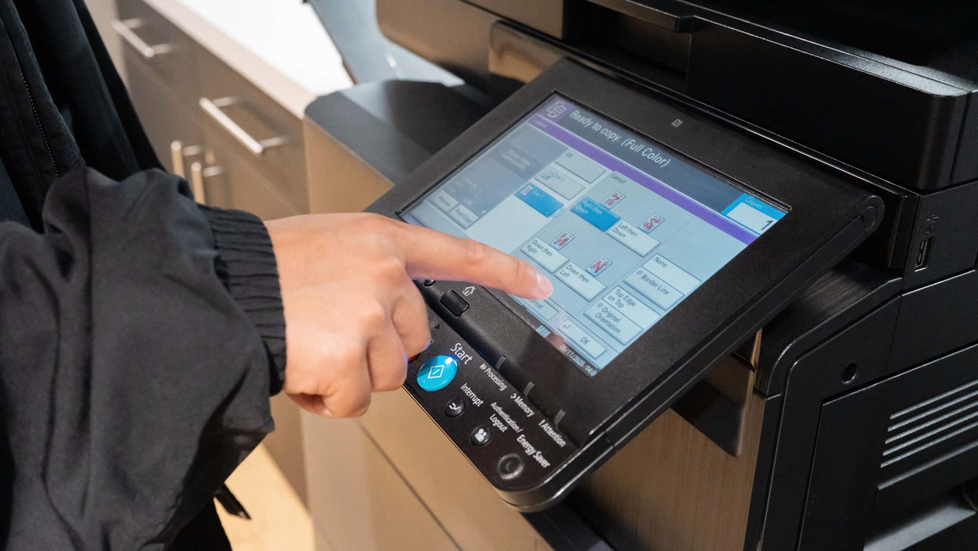 Hand using a touchscreen printer control panel in an office setting