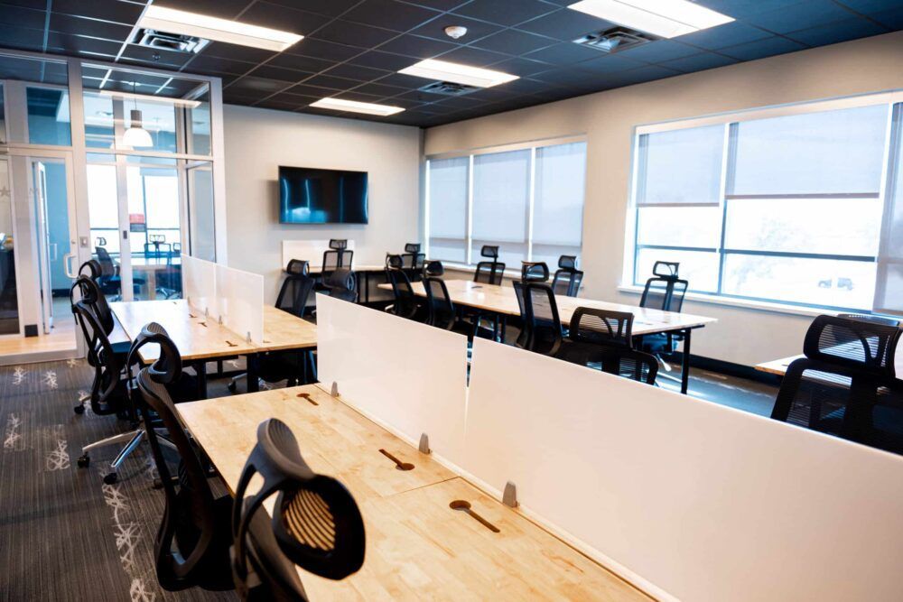 Modern office with desks, swivel chairs, and large windows in a bright open workspace