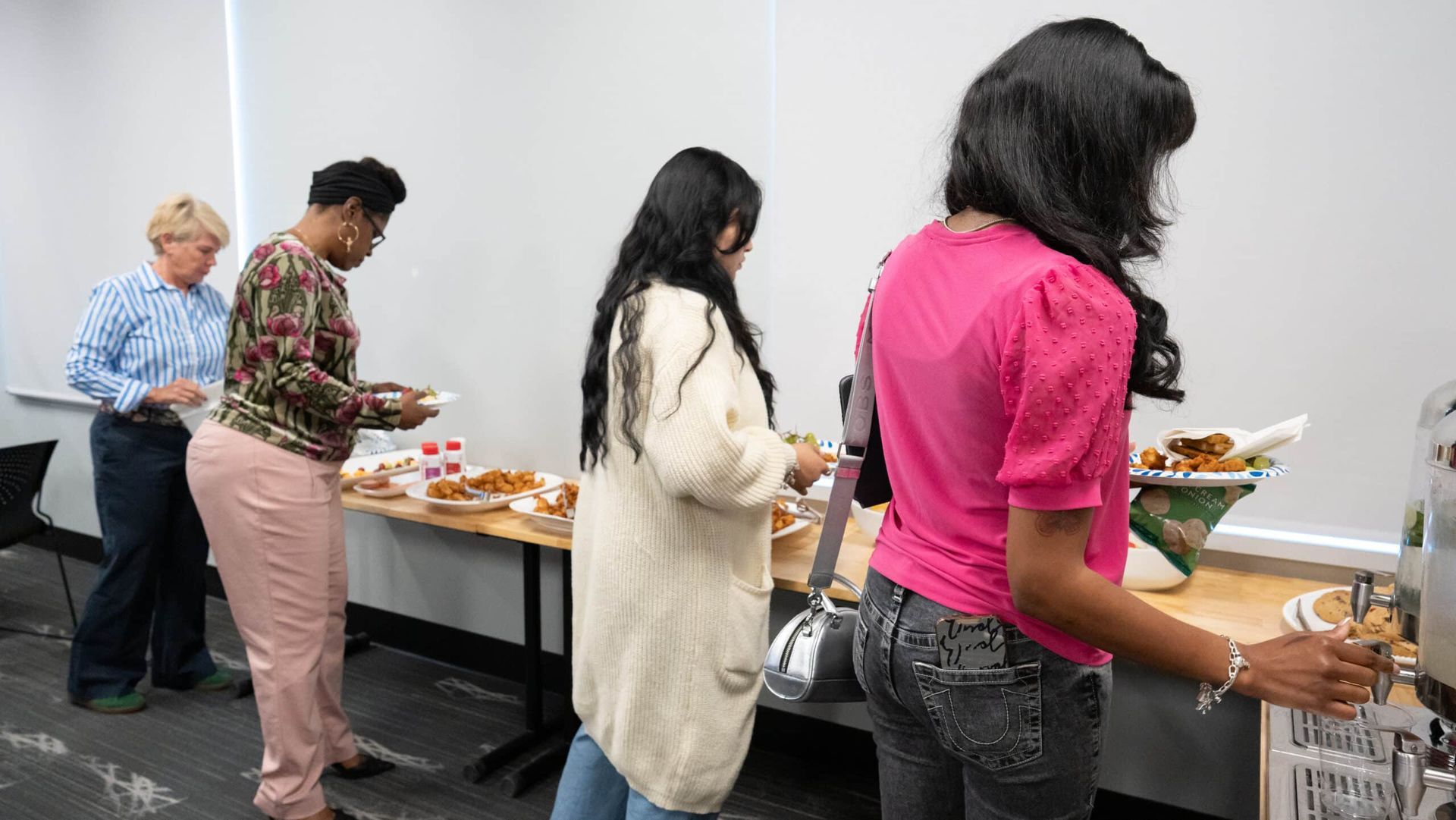 People serving themselves from a buffet table in a bright indoor room