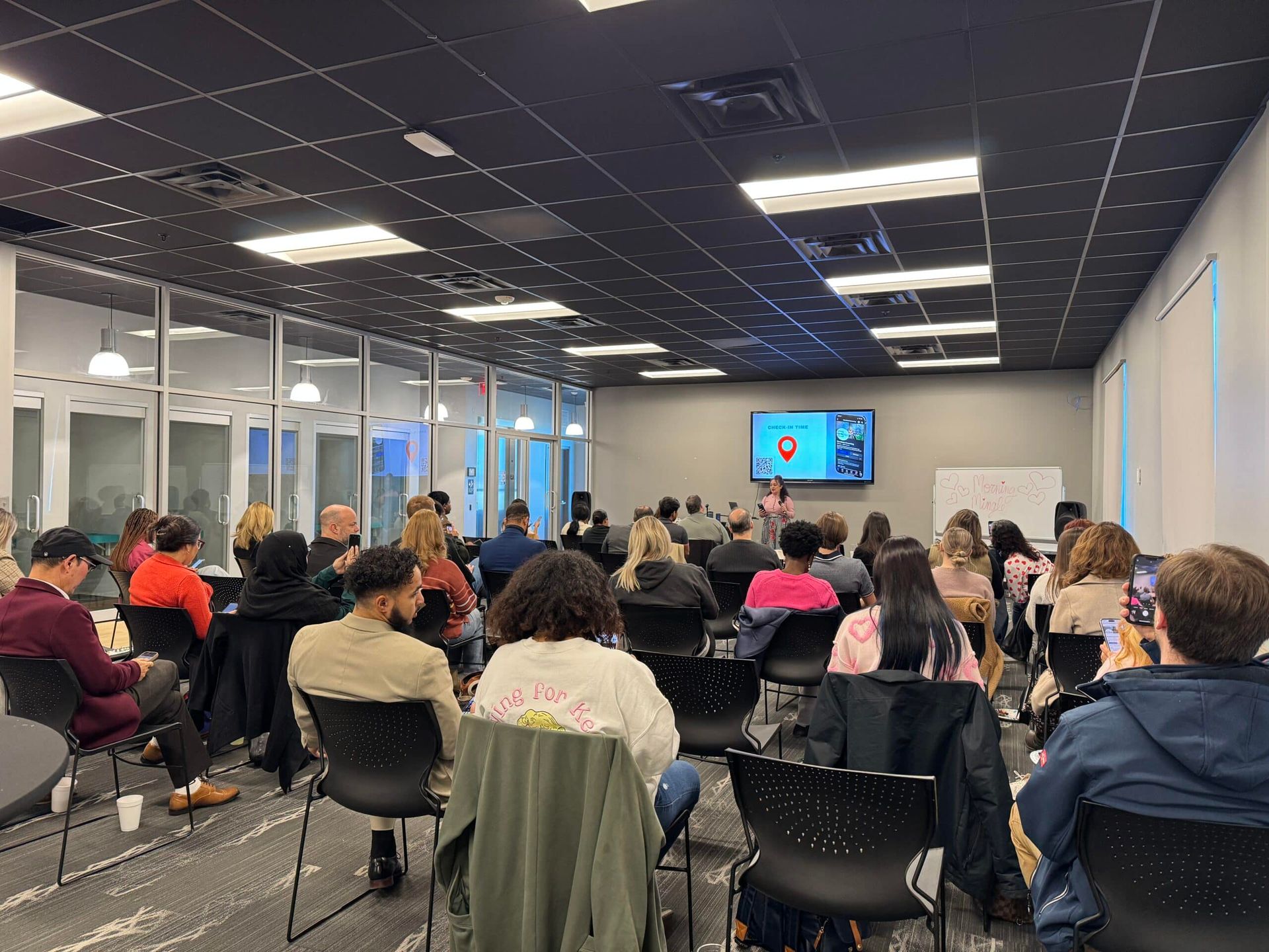 Audience seated in a meeting room watching a presentation on a screen