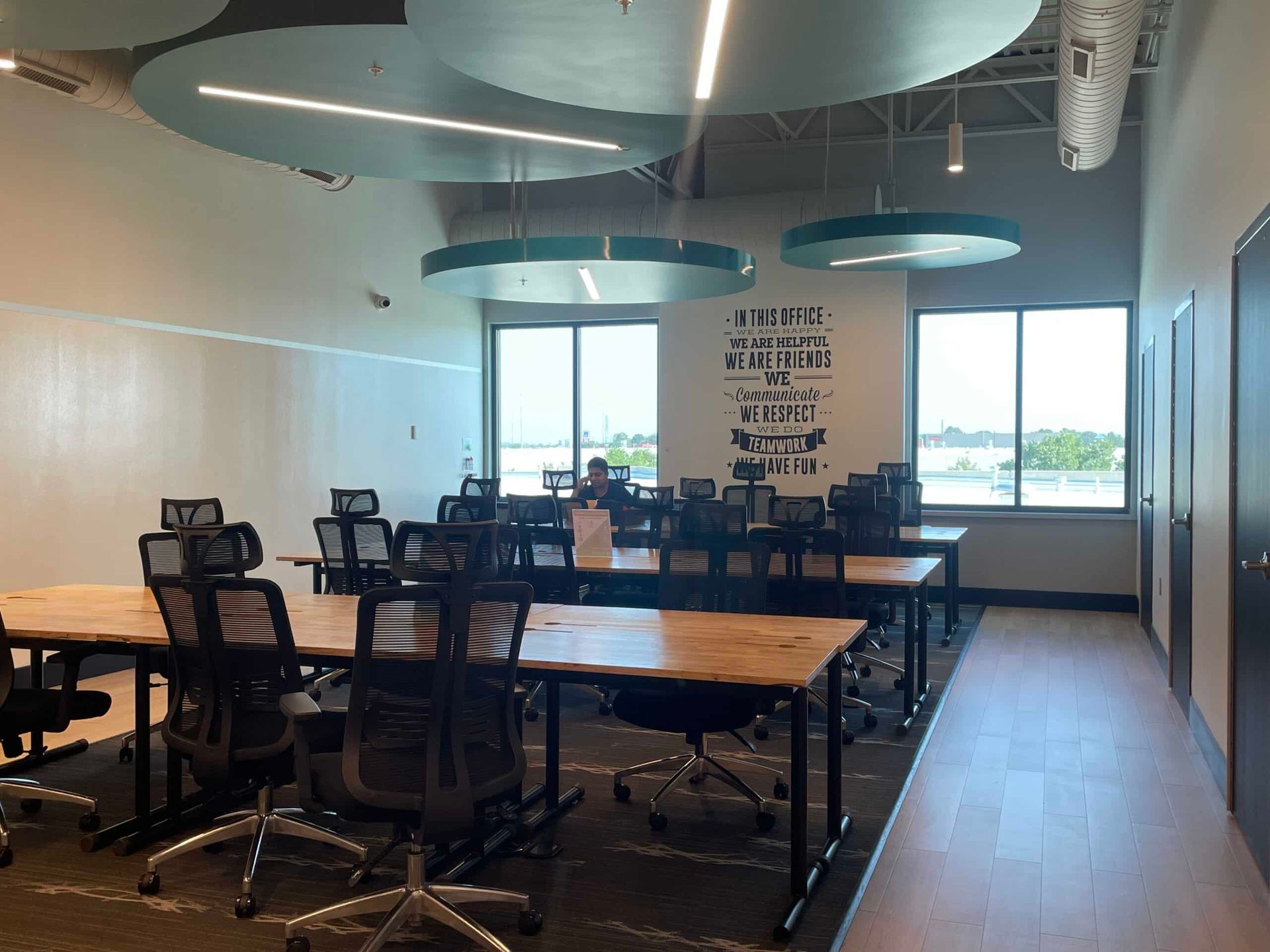 Modern classroom with desks, swivel chairs, and large windows under circular ceiling lights