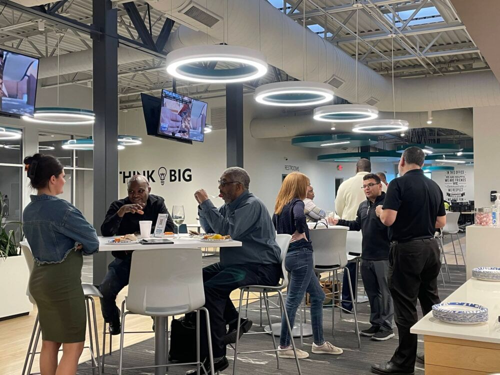 People networking at standing tables in a modern office space with hanging ring lights