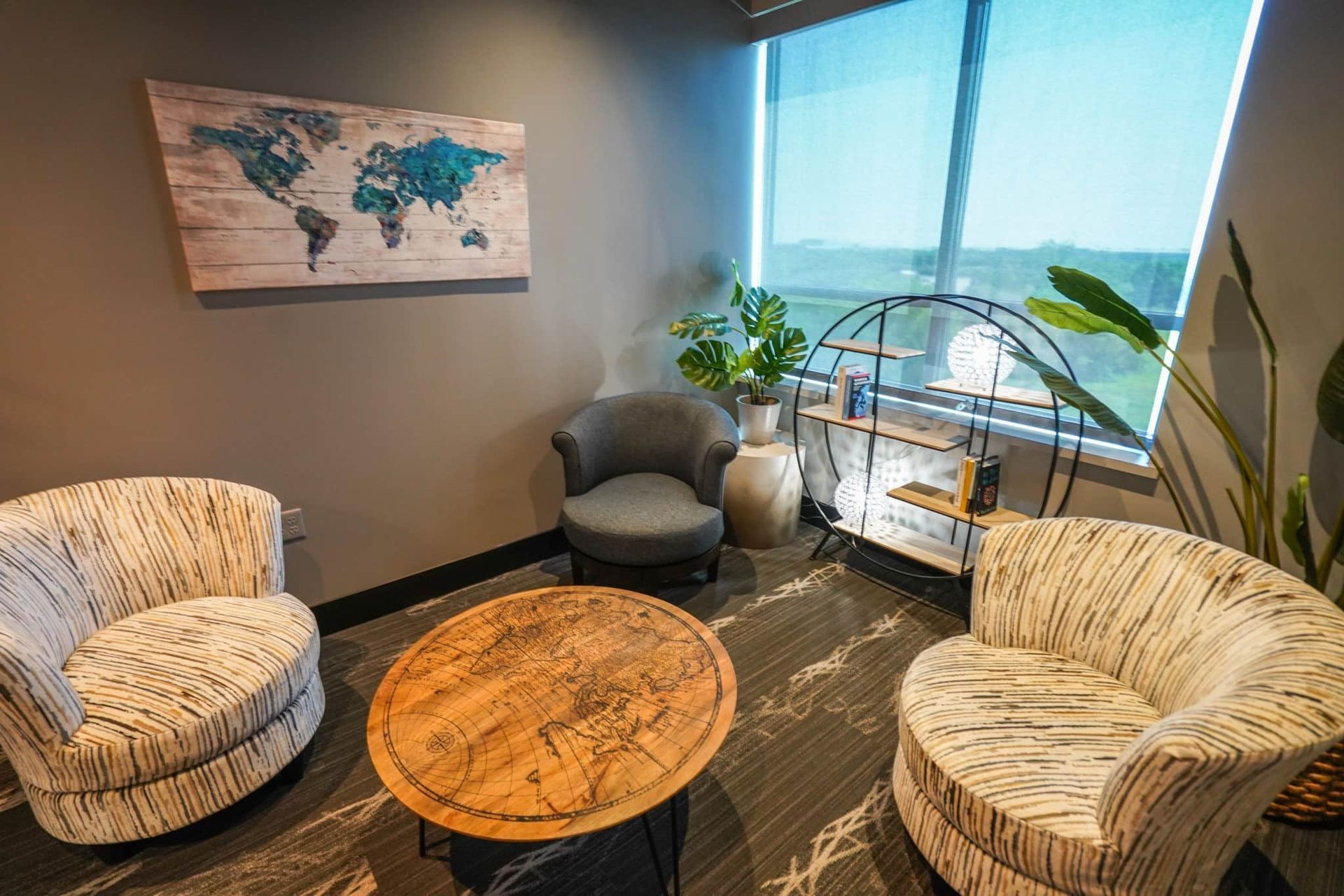 Cozy office seating area with patterned chairs, round wood table, and world map wall art by a window