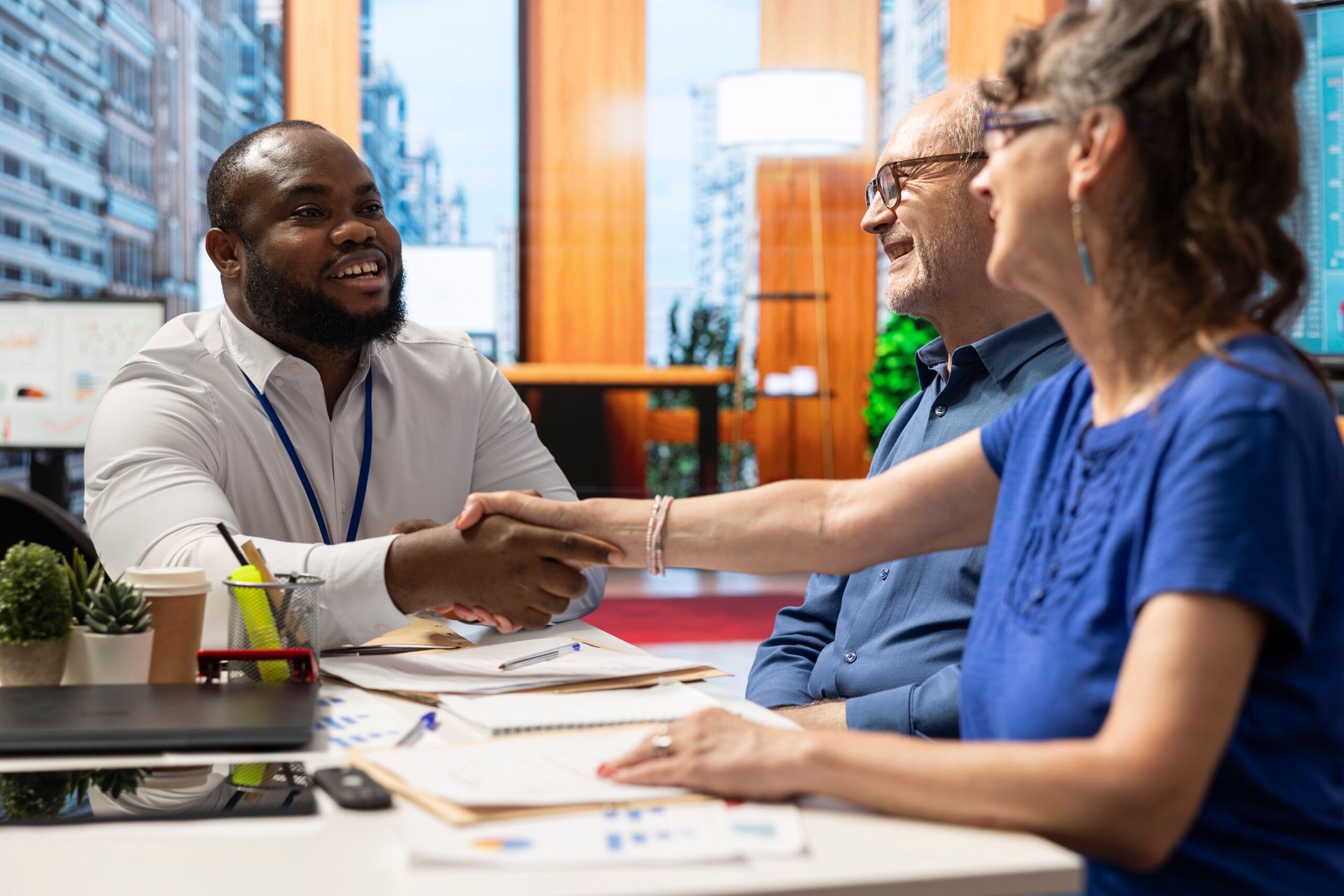 People shaking hands across a conference table in a bright office meeting room