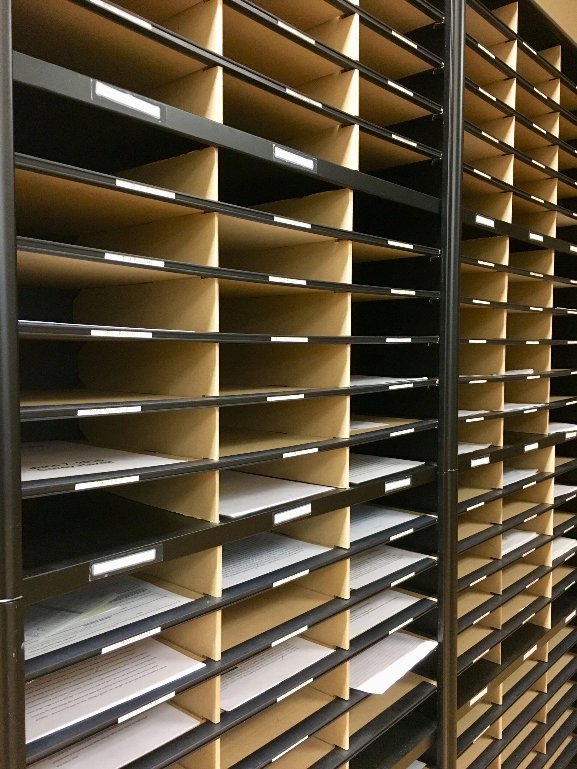 Shelves of empty mail slots with brown dividers and white trays in an office organizer