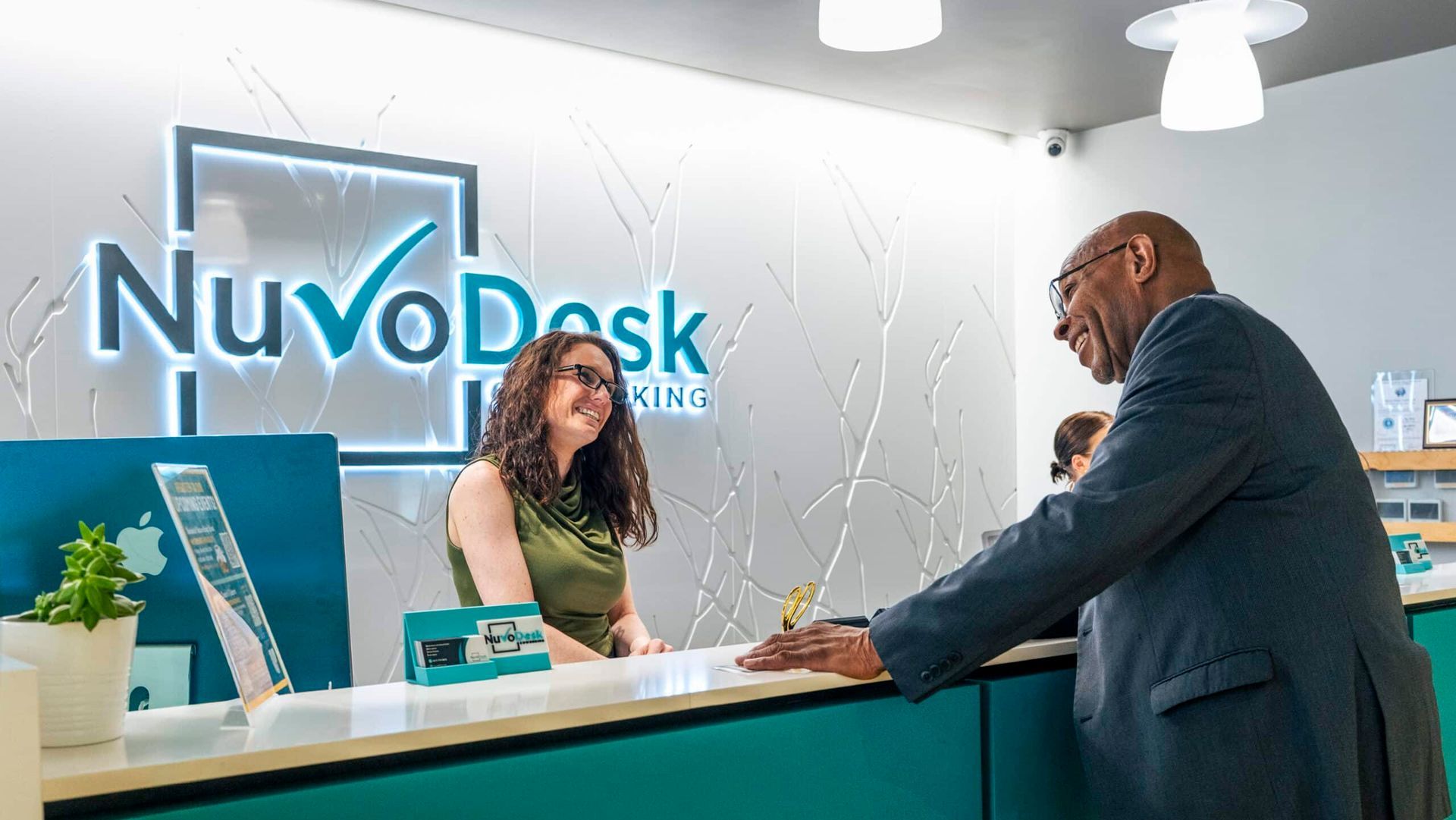Reception desk with a smiling clerk helping a customer at a NuvoDesk office front counter