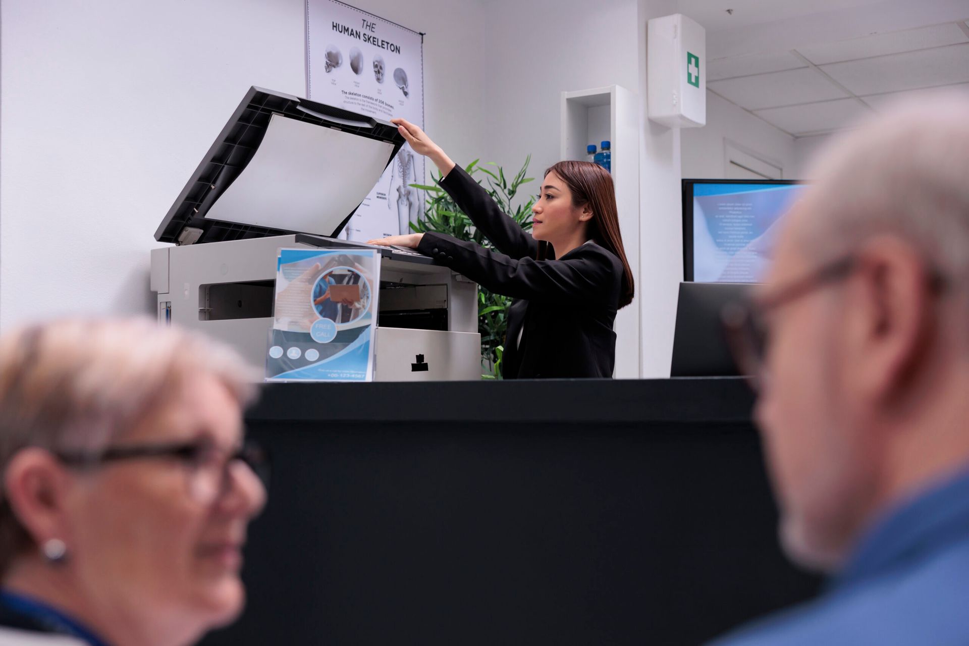 Presenter demonstrating a device at a trade show booth while two attendees watch in the foreground