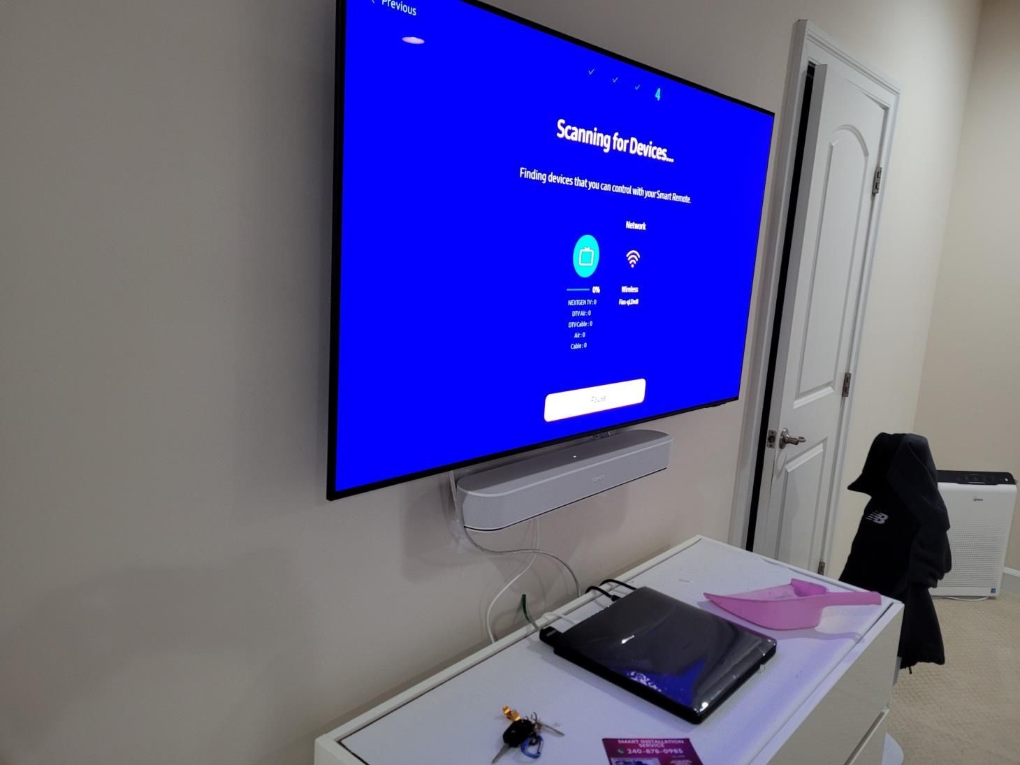Wall-mounted TV displaying a blue login screen above a desk with a laptop and chair in a room