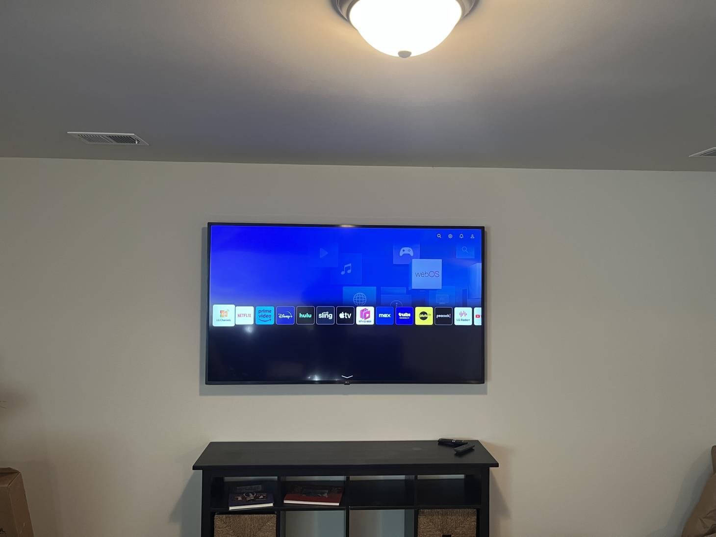 Wall-mounted TV displaying a home screen above a black media console in a living room.
