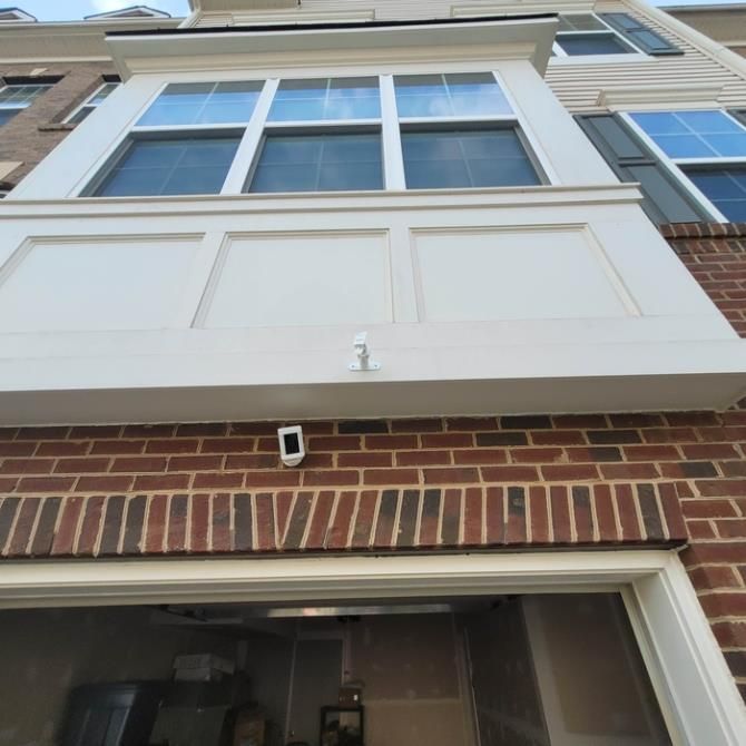 Exterior of a multi-story brick and white townhouse with large windows and a balcony