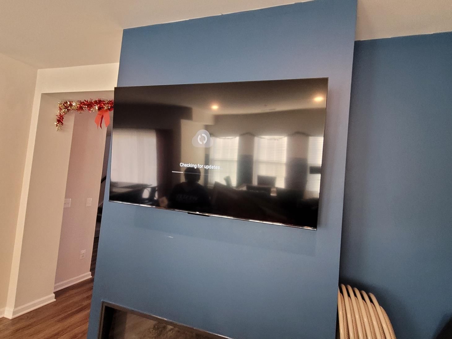 Living room with a wall-mounted TV on a blue accent wall and a doorway to the left