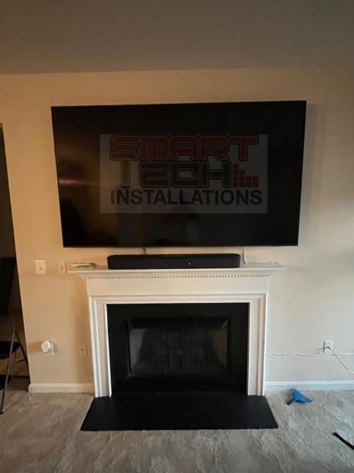 Living room with wall-mounted TV above a white fireplace and black hearth
