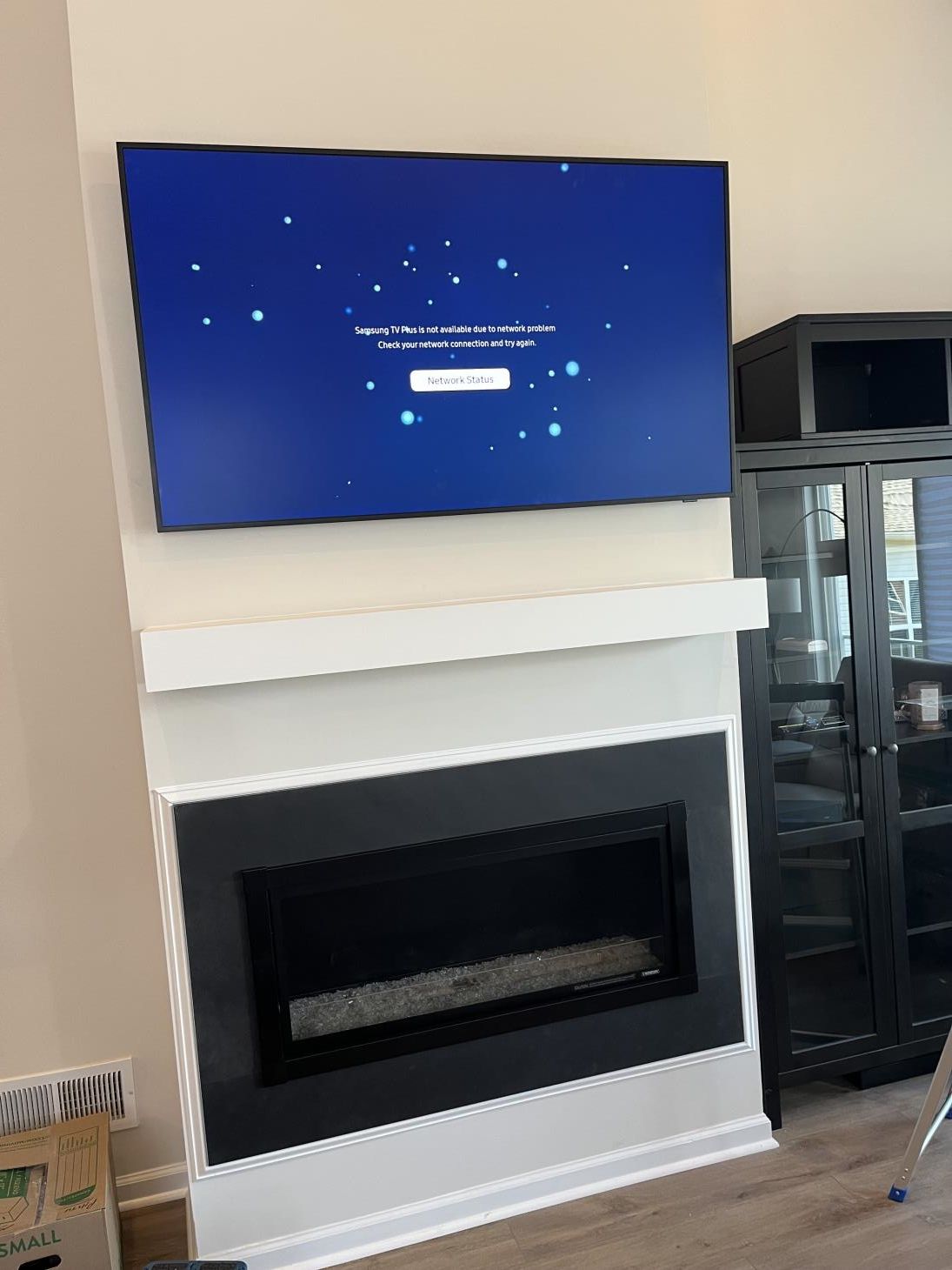Living room fireplace with a wall-mounted TV showing a blue screen above it