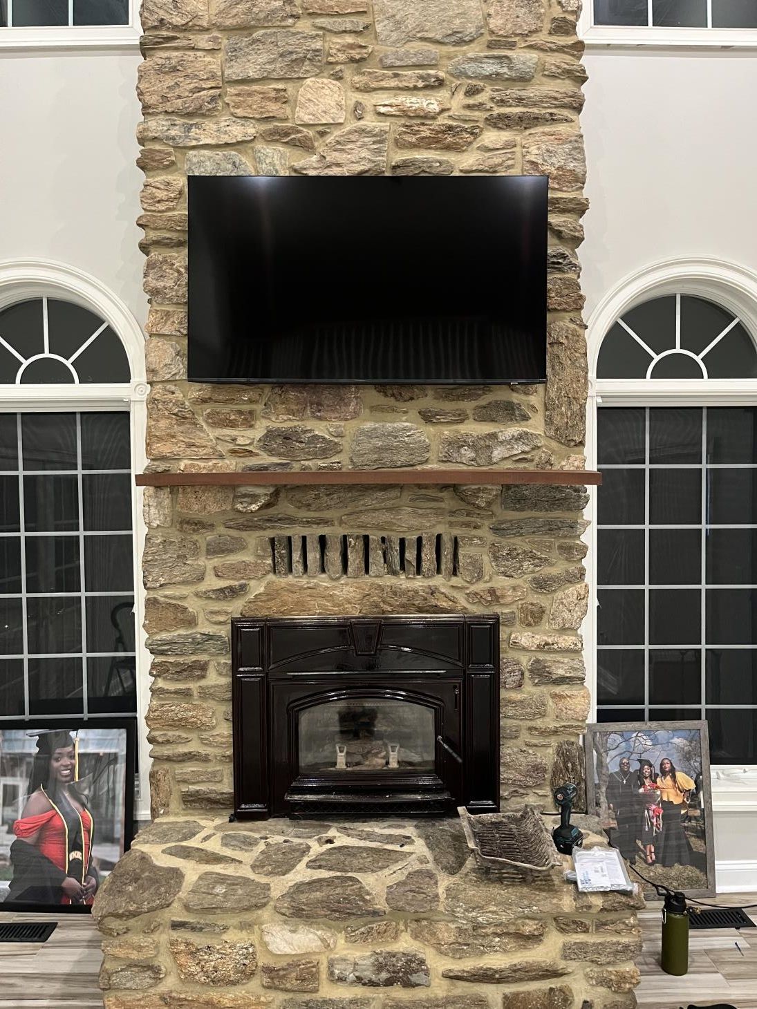 Stone fireplace wall with mounted TV and arched windows on both sides