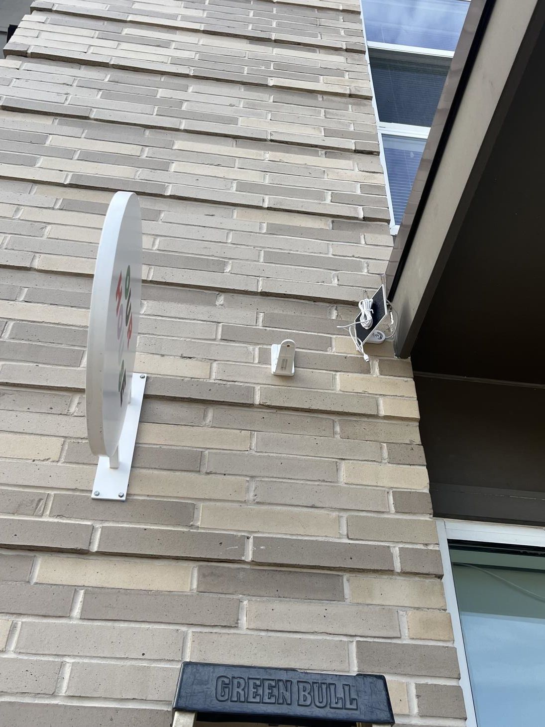 Close-up of a brick house wall with a white security camera mount and a 