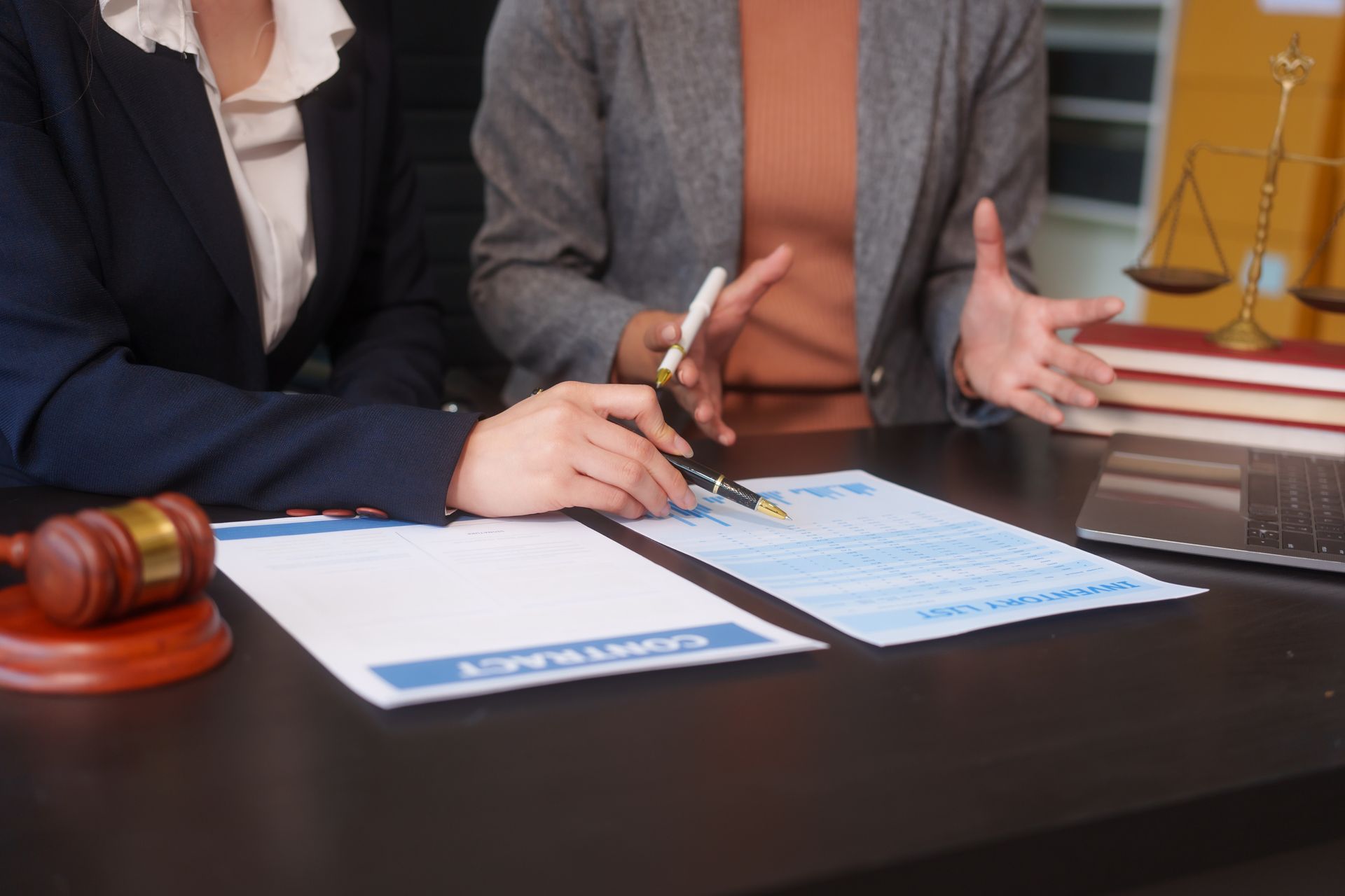 A close-up of two female lawyers' hands working at a desk, handling legal documents. A close-up of two female lawyers' hands working at a desk, handling legal documents.