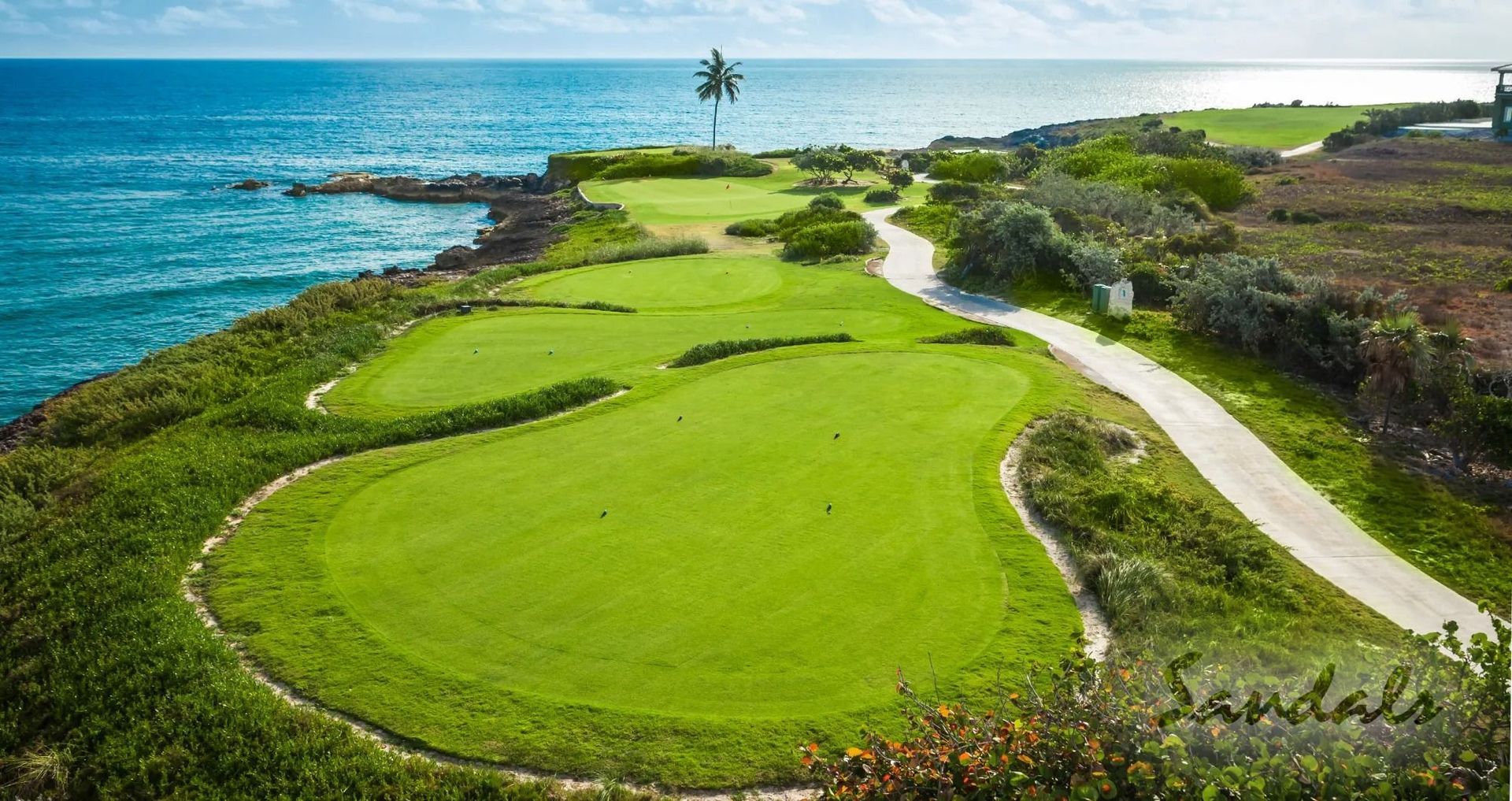 Lush green tee boxes next to the ocean at Sandals Emerald Bay Golf Course.