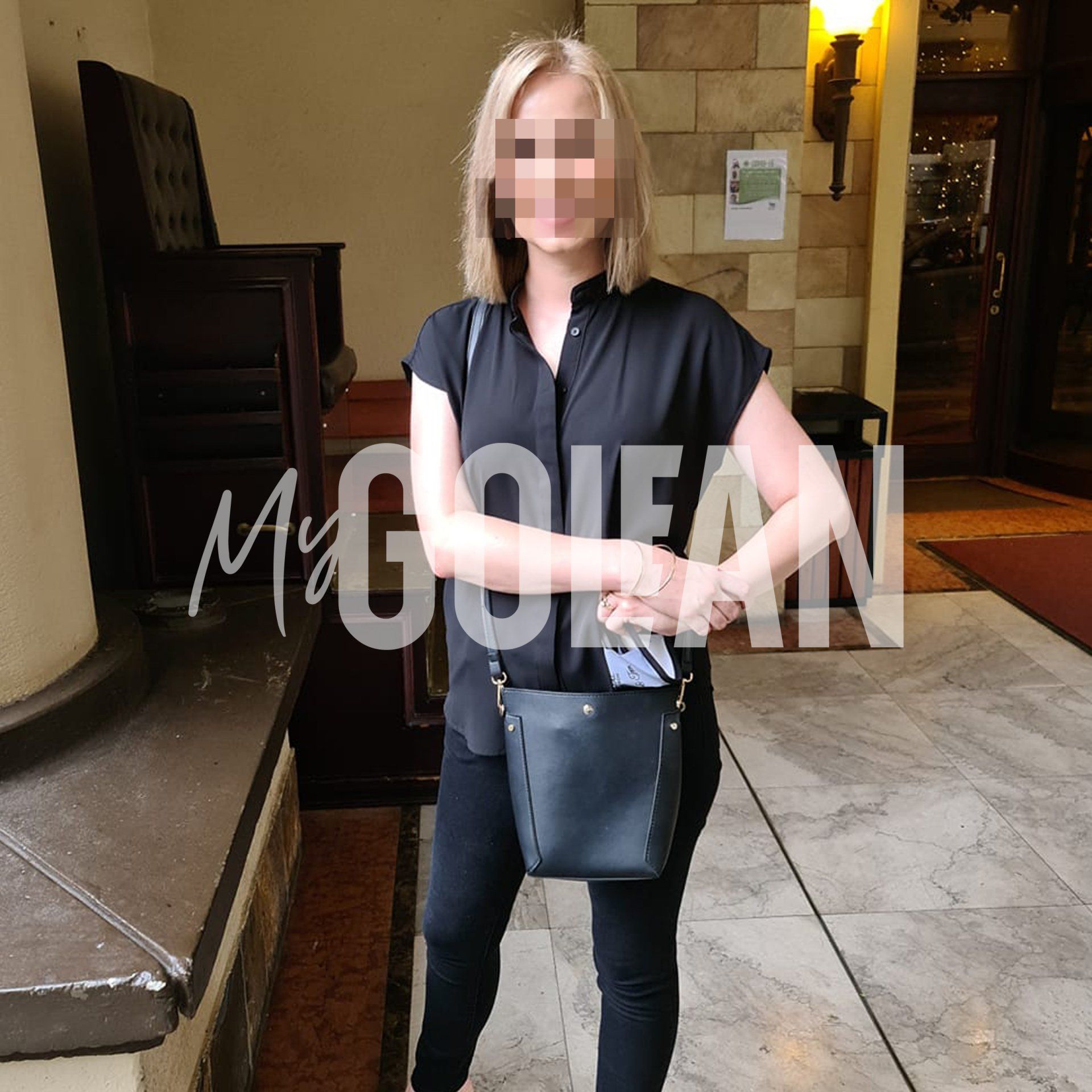 A woman wearing a black shirt and black pants is holding a black bag