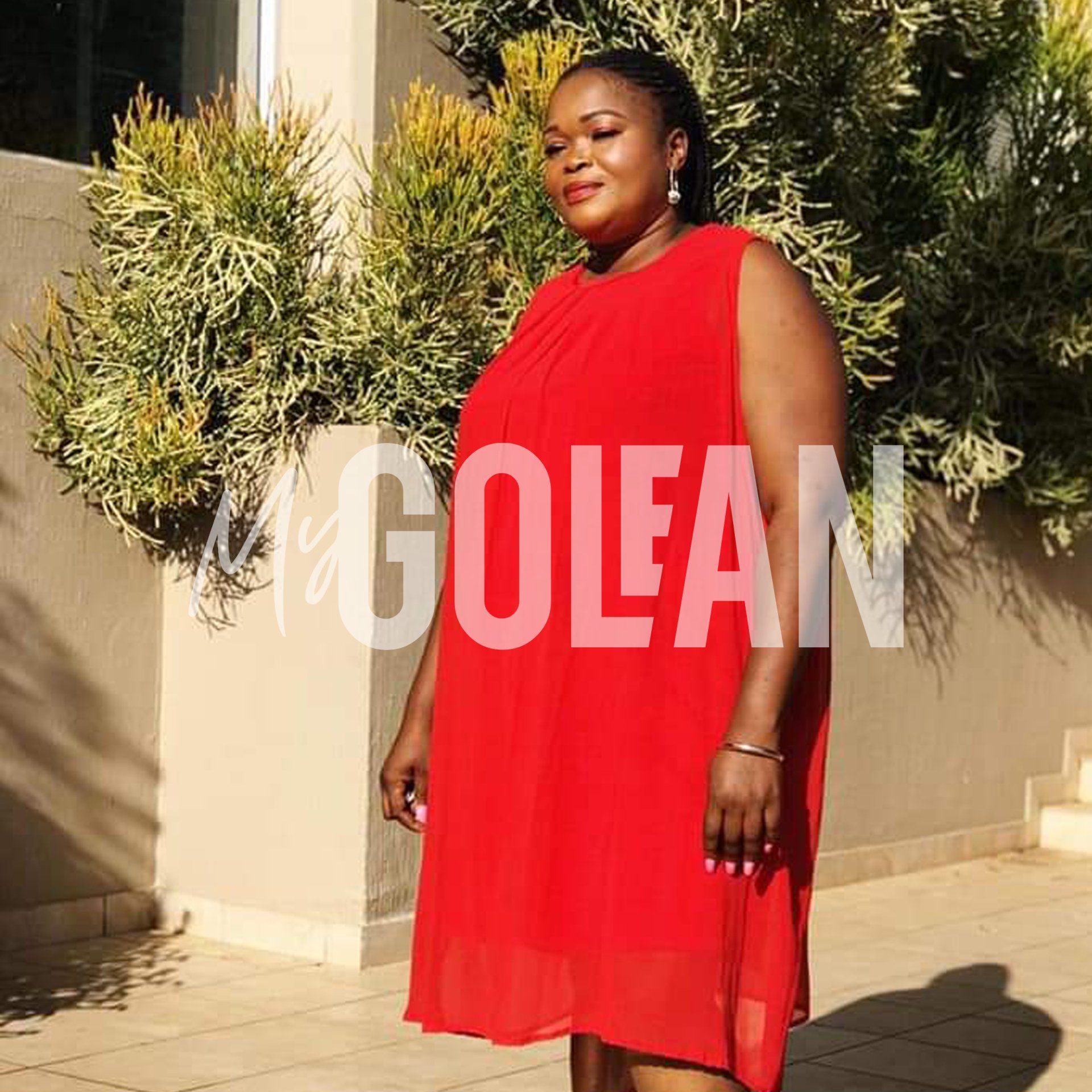 A woman in a red dress is standing in front of a wall that says golean