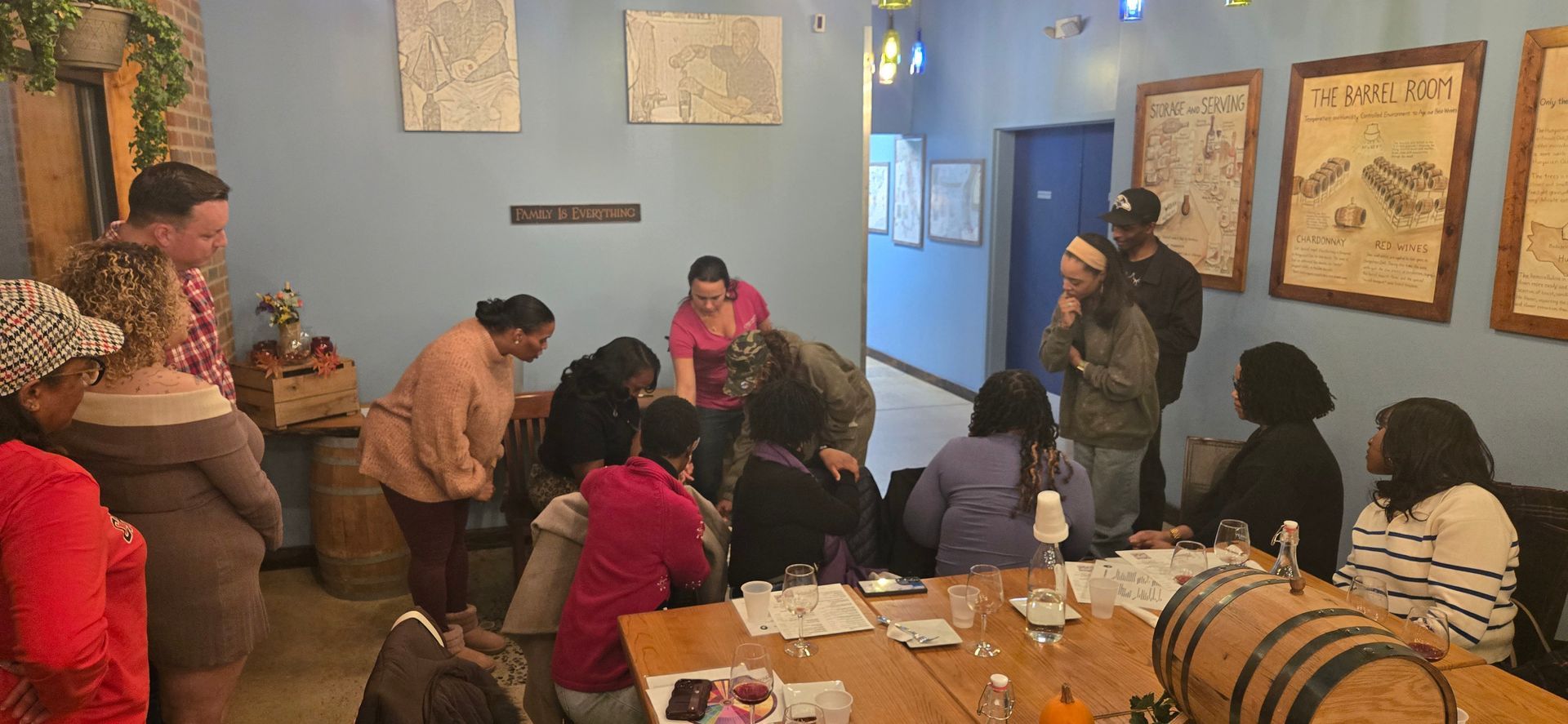 People seated around tables in a colorful room, gathered for a group activity or class.