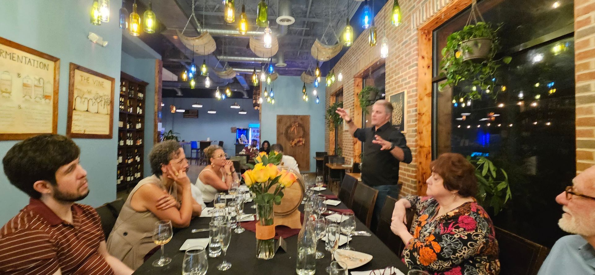 People dining together at a candlelit restaurant table with hanging lights and brick walls