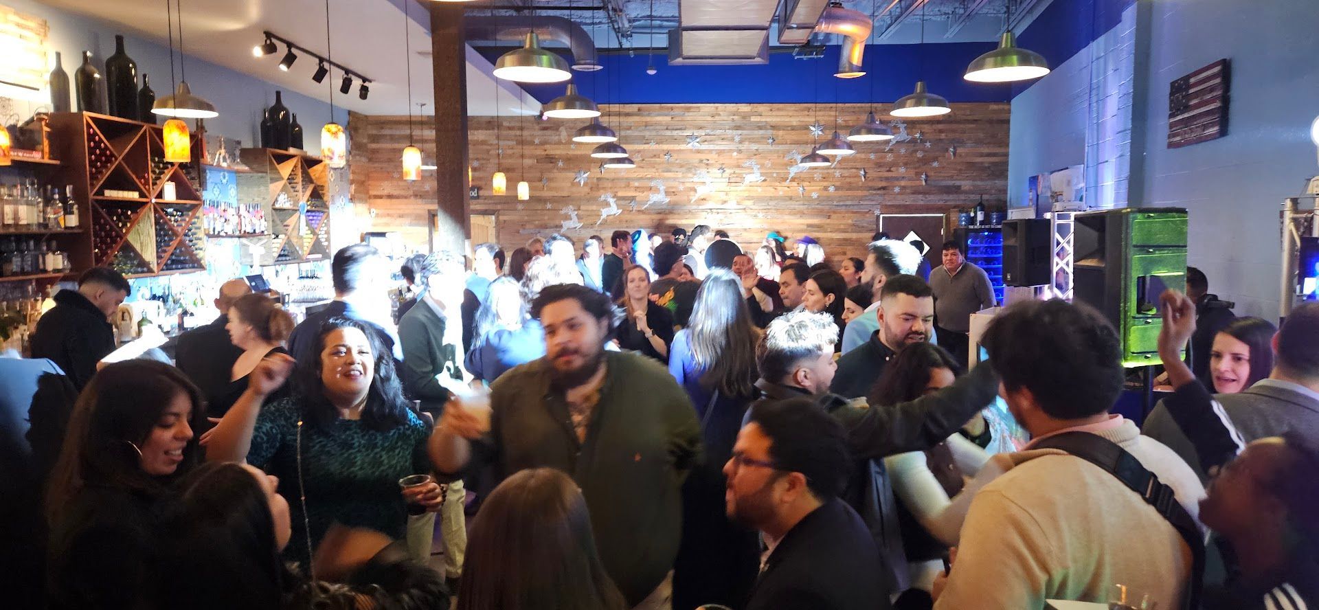 Crowded bar or café with people socializing under warm lights and a blue ceiling