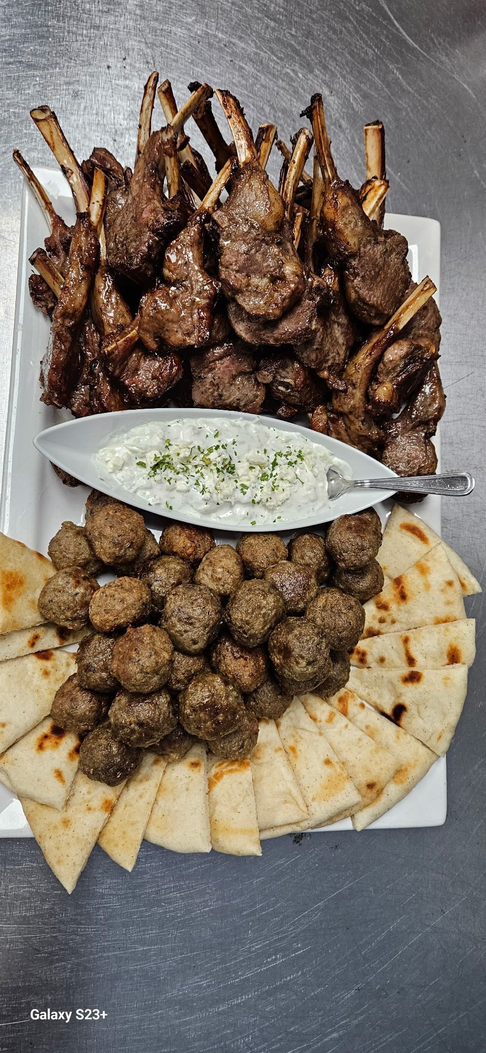 Grilled meat skewers and kebabs arranged on a platter with pita bread and dipping sauce