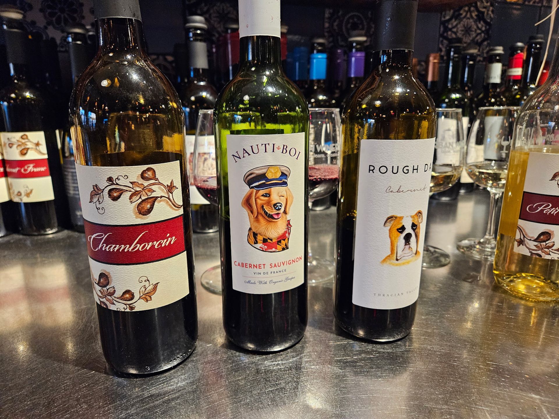 Assorted wine bottles lined up on a bar counter, with labels facing the camera.