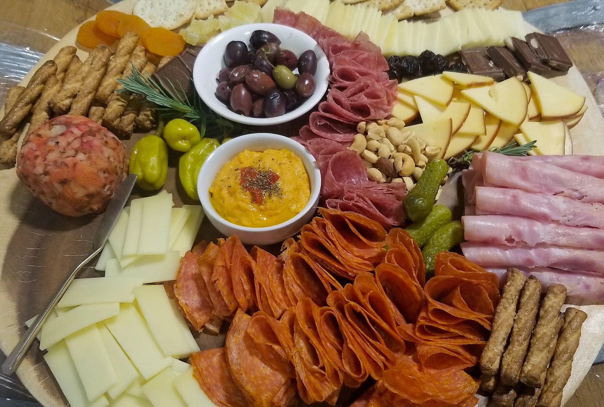 Charcuterie board with assorted cheeses, olives, crackers, meats, and dips arranged on a platter
