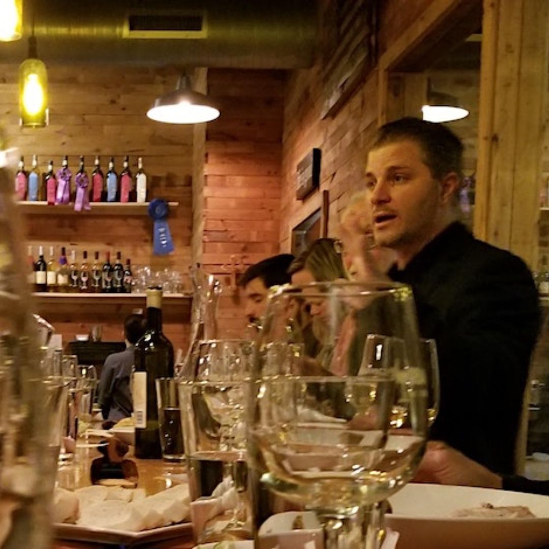 People dining in a cozy restaurant, with wine glasses and warm brick walls in the background