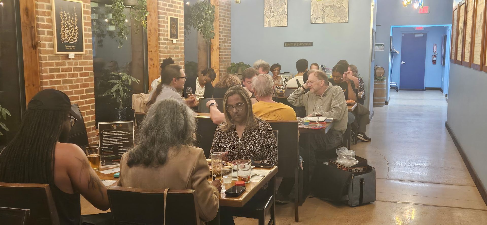 Crowded restaurant dining area with people seated at tables under warm lights and blue walls