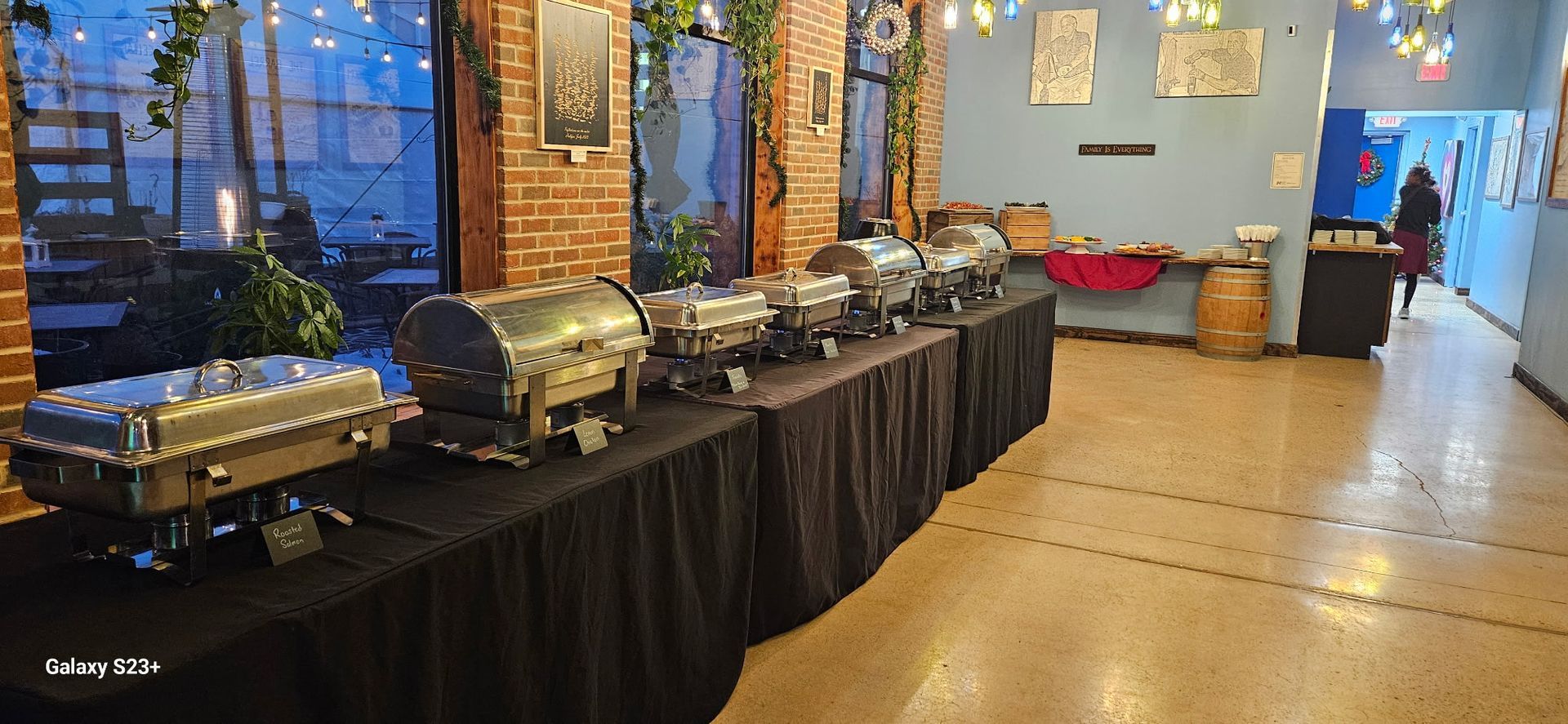 Buffet table with silver chafing dishes and red seating in a brick-walled event space