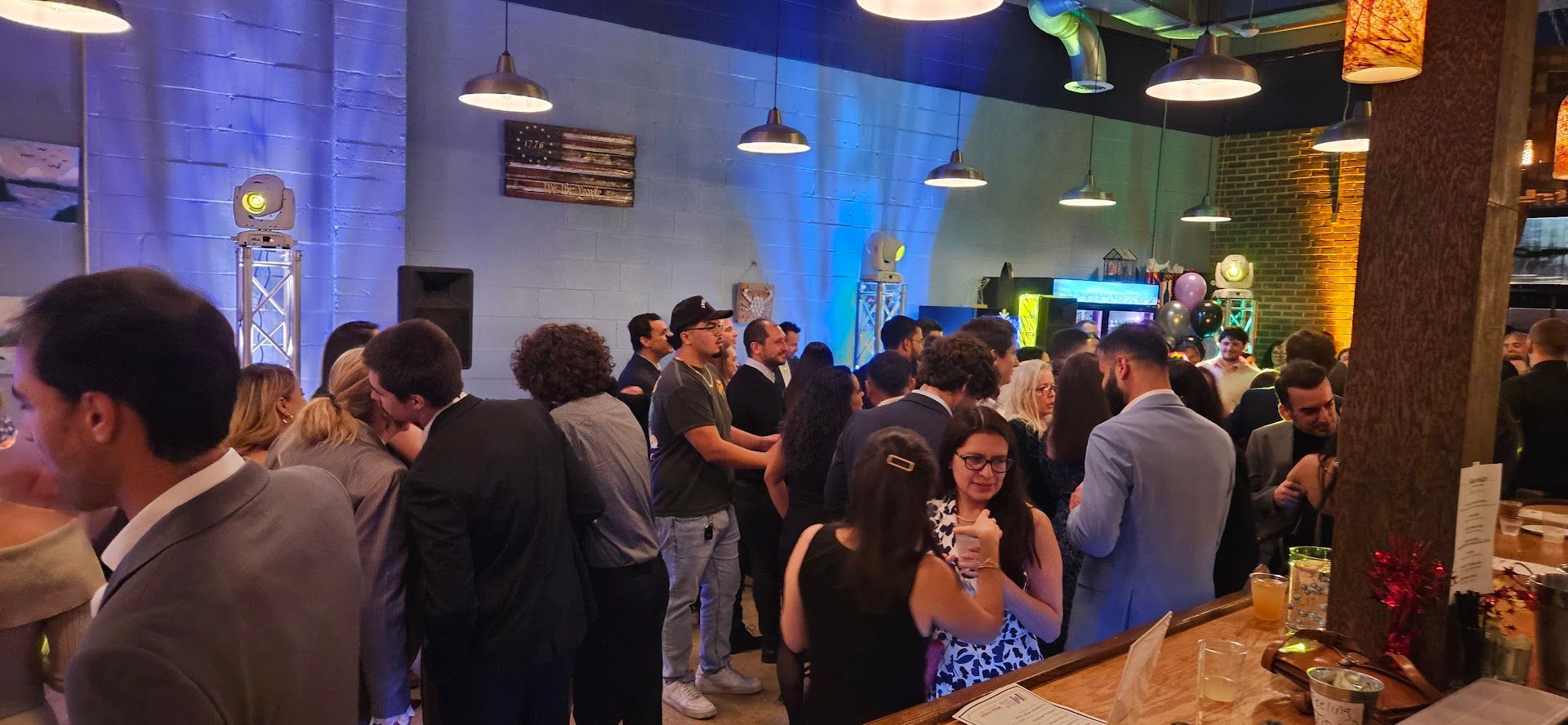Crowded indoor bar with people socializing under blue and warm hanging lights