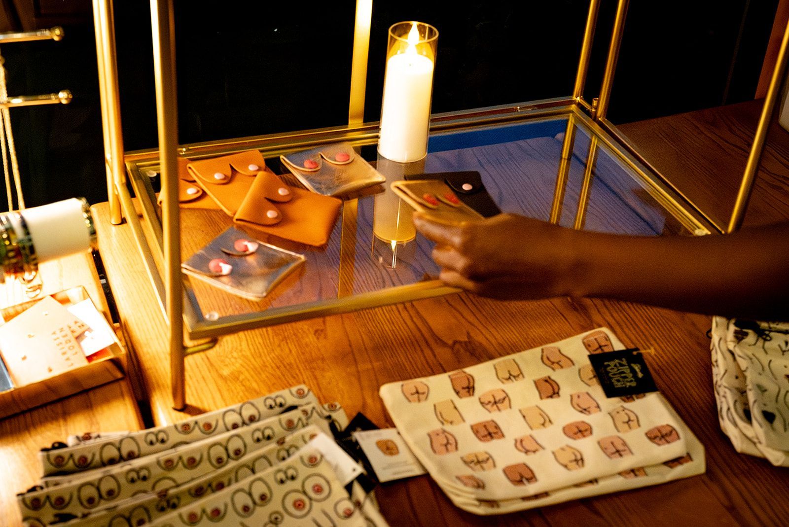 Person reaches toward tarot cards on a lit table with a candle and patterned cloths