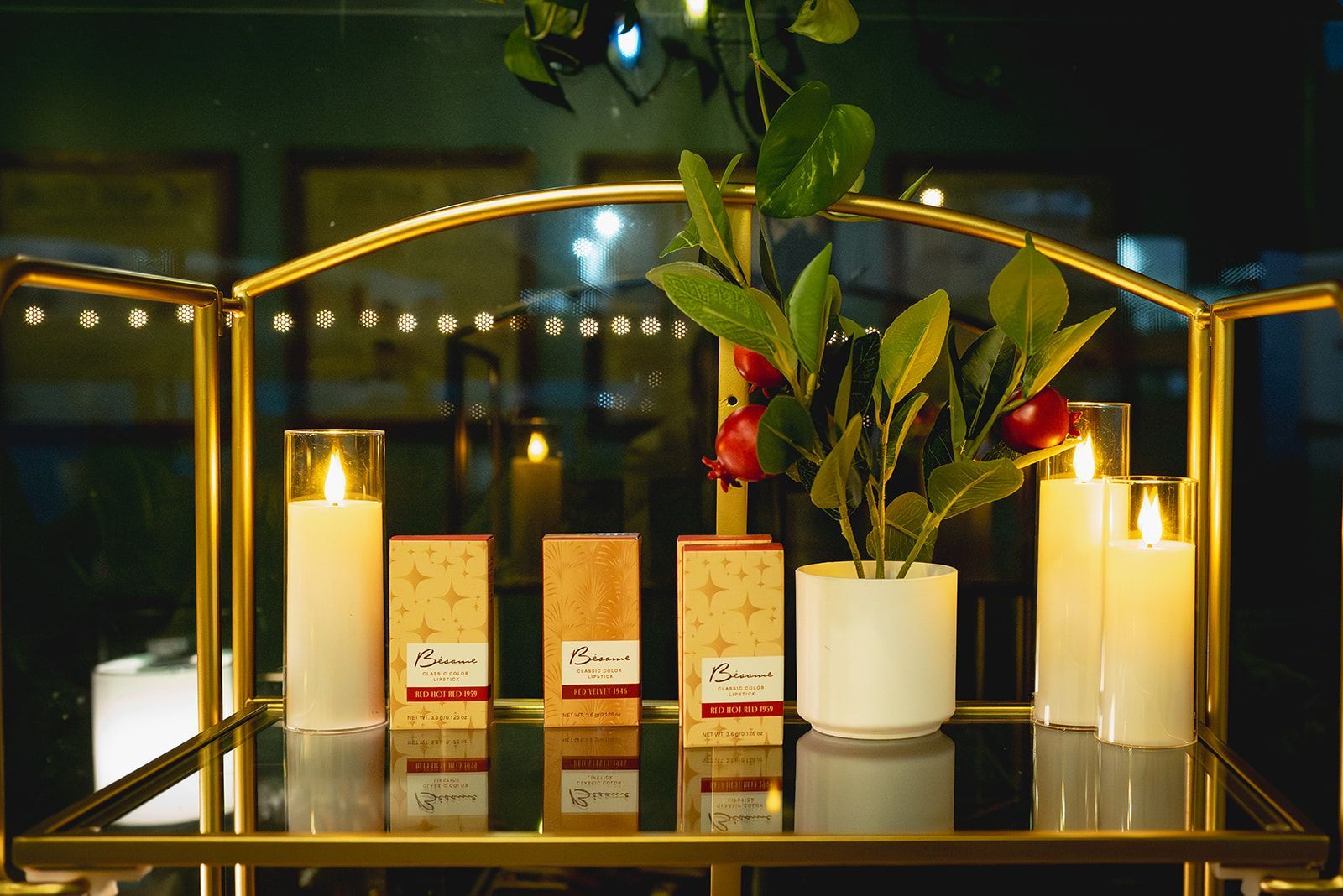 Elegant shelf display with candles, boxed products, and a white vase of flowers under warm lights