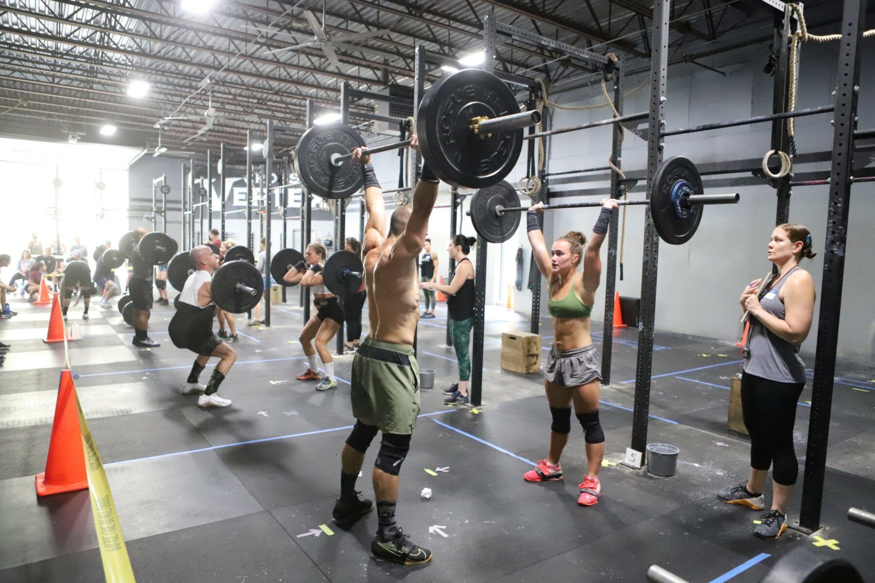 A group of people are lifting weights during a CrossFit competition at CrossFit Vertex gym