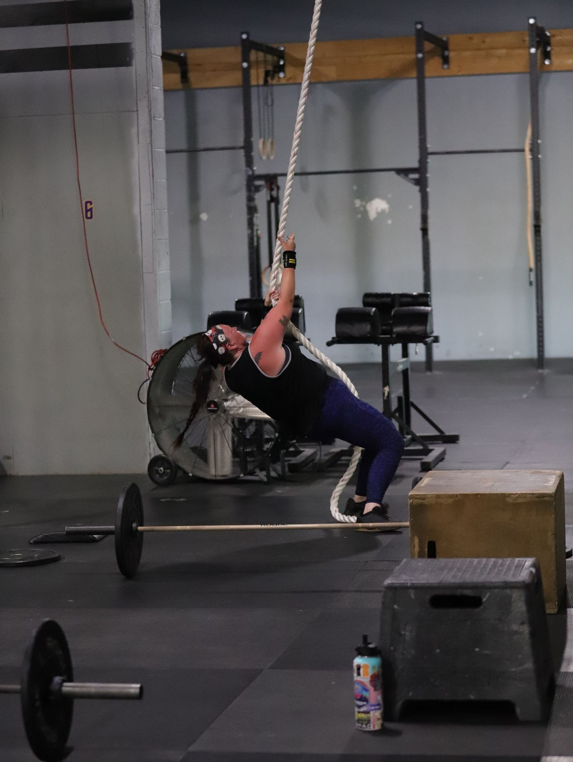 Woman performs a rope climb.