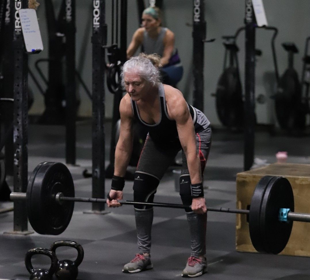 A woman is lifting a barbell in the gym at CrossFit Vertex in Olyphant, PA