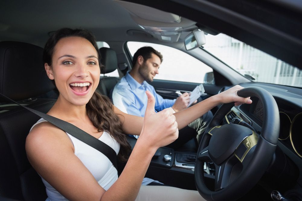 A Woman is Giving a Thumbs Up While Sitting in a Car Next to a Man — NT Driving Academy in Woolner, NT