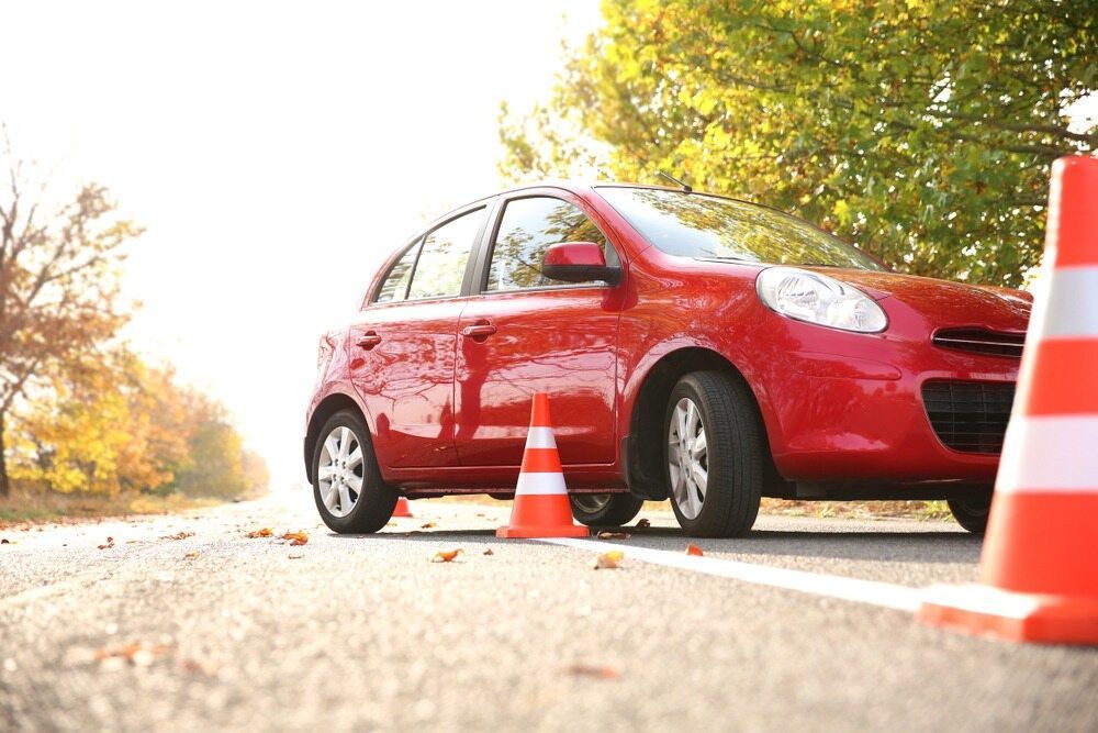 A Red Car is Parked on the Side of the Road Next to Traffic Cones — NT Driving Academy in Woolner, NT
