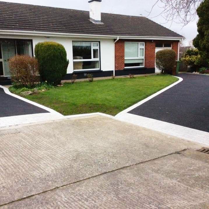 House with asphalt driveways, green lawn, brick and white exterior.